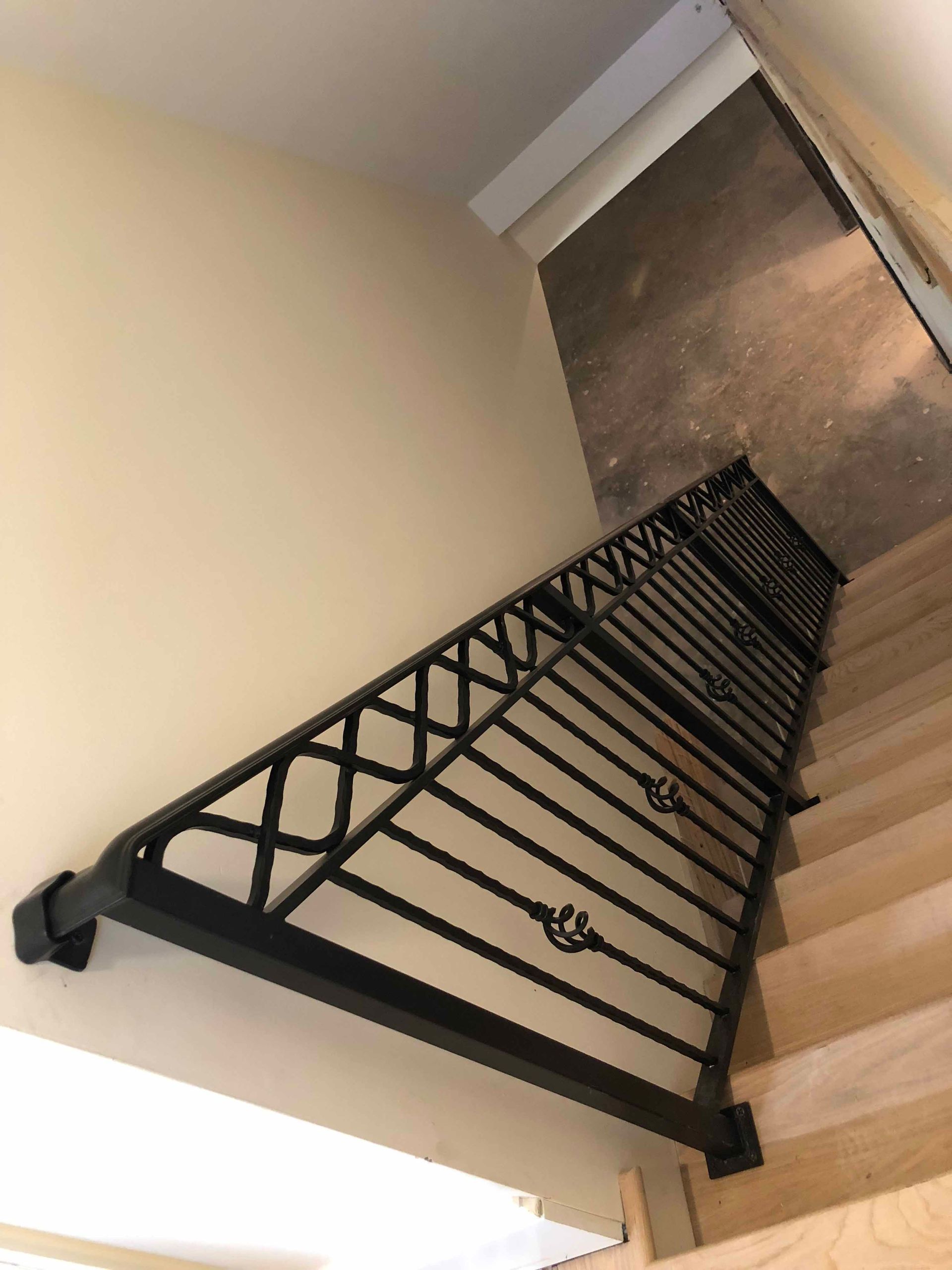 A staircase with a wrought iron railing and wooden steps