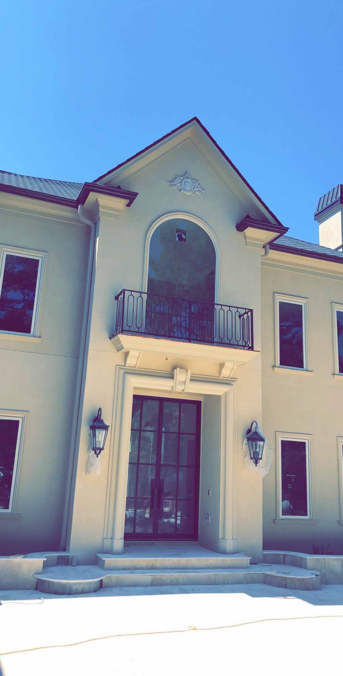 A large house with a balcony and a blue sky in the background.
