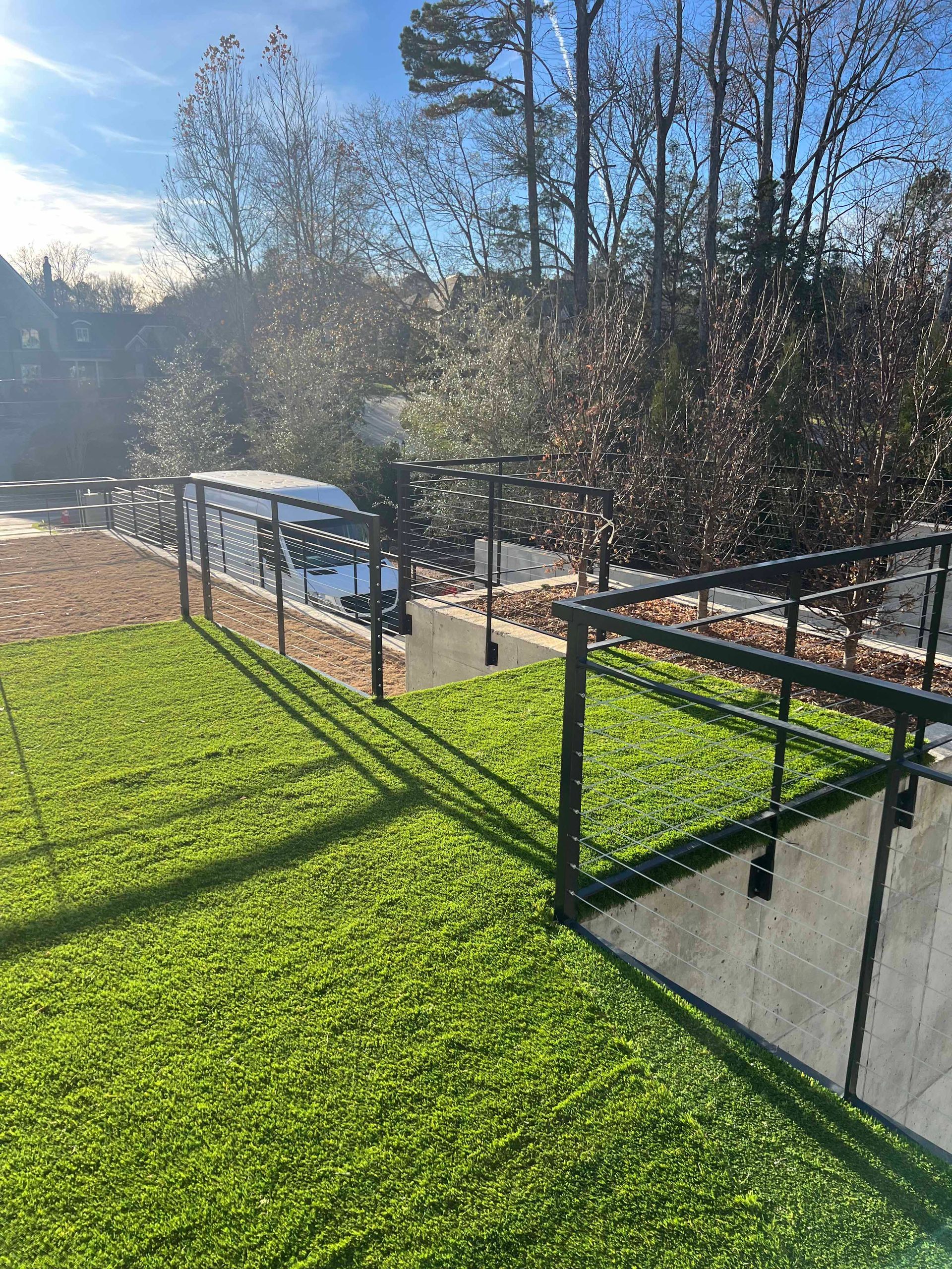 A fence surrounds a lush green field with trees in the background.