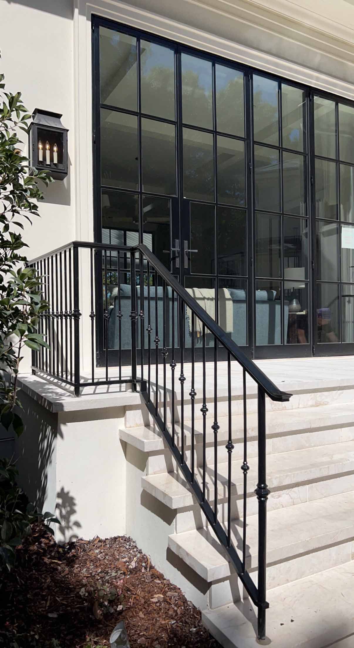 A staircase leading up to a screened in porch with a wrought iron railing.