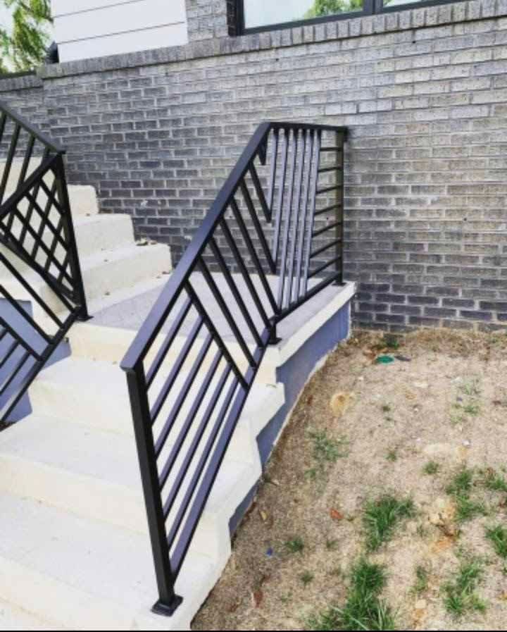A black railing on a set of stairs next to a brick wall.