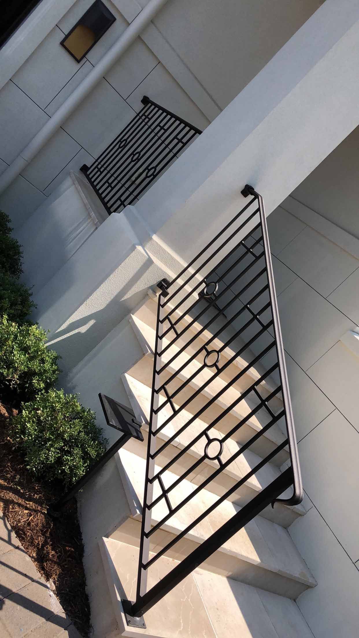A wrought iron railing surrounds a set of stairs leading up to a house.