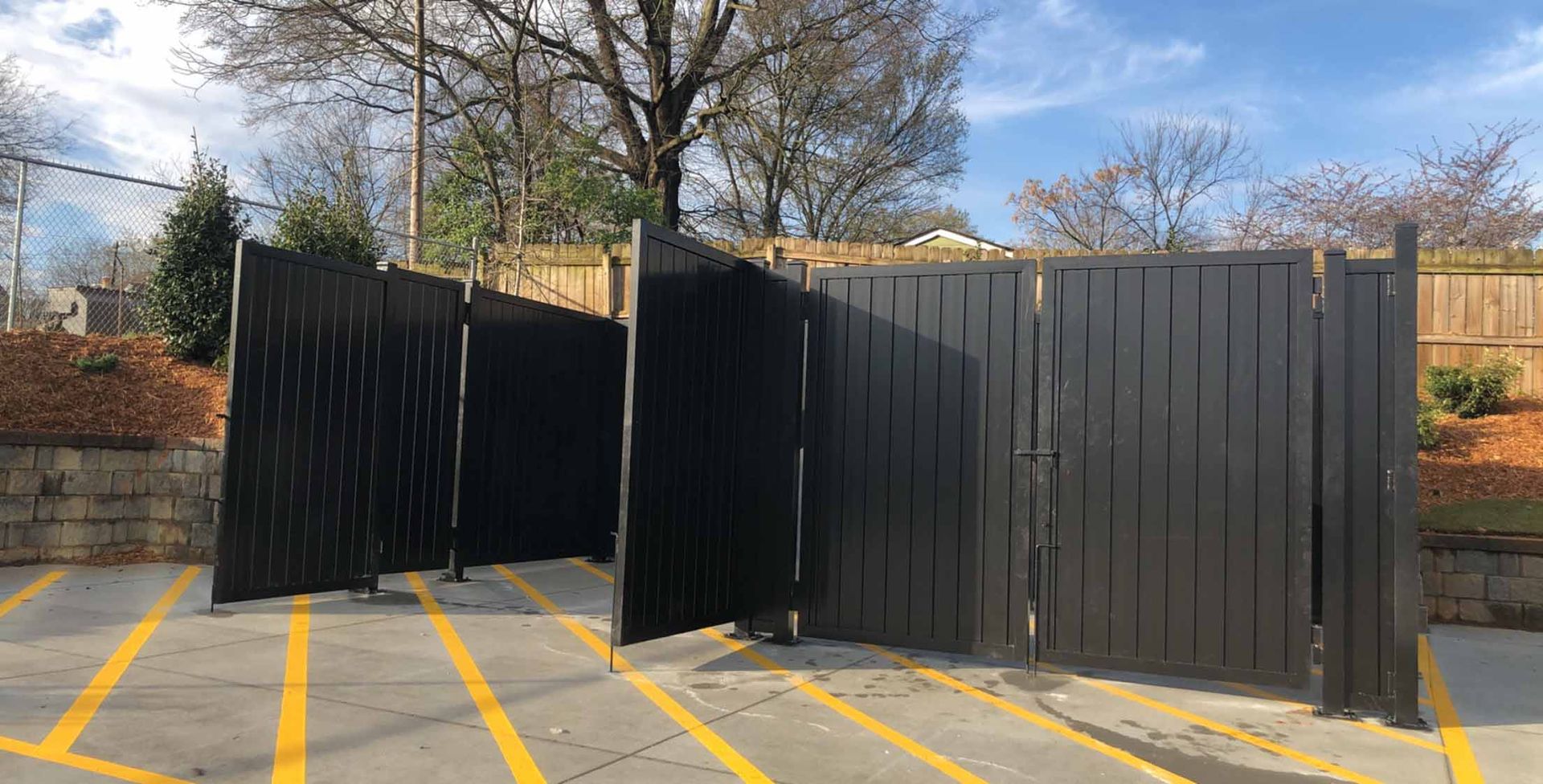 A black fence is sitting in a parking lot next to a tree.