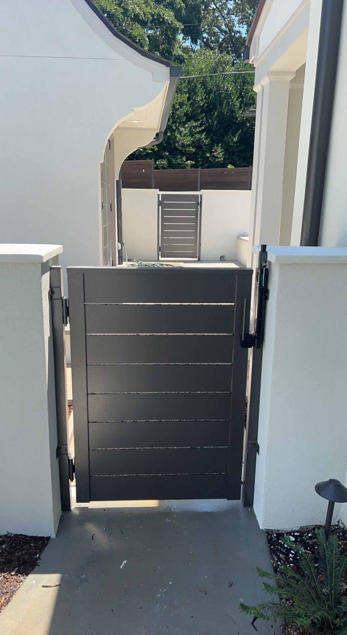 A black gate is leading to a white house.