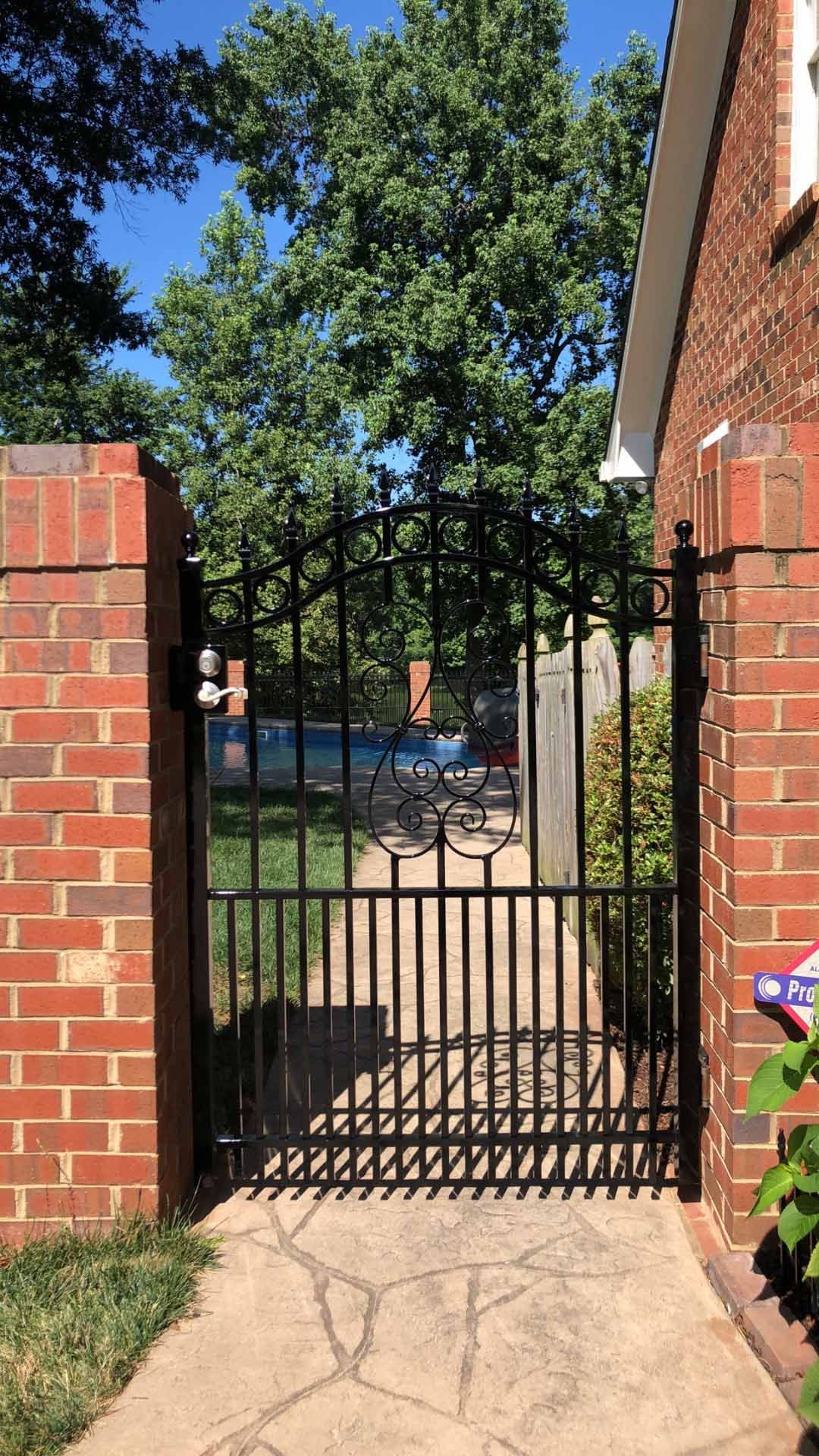 A wrought iron gate is leading to a brick house.