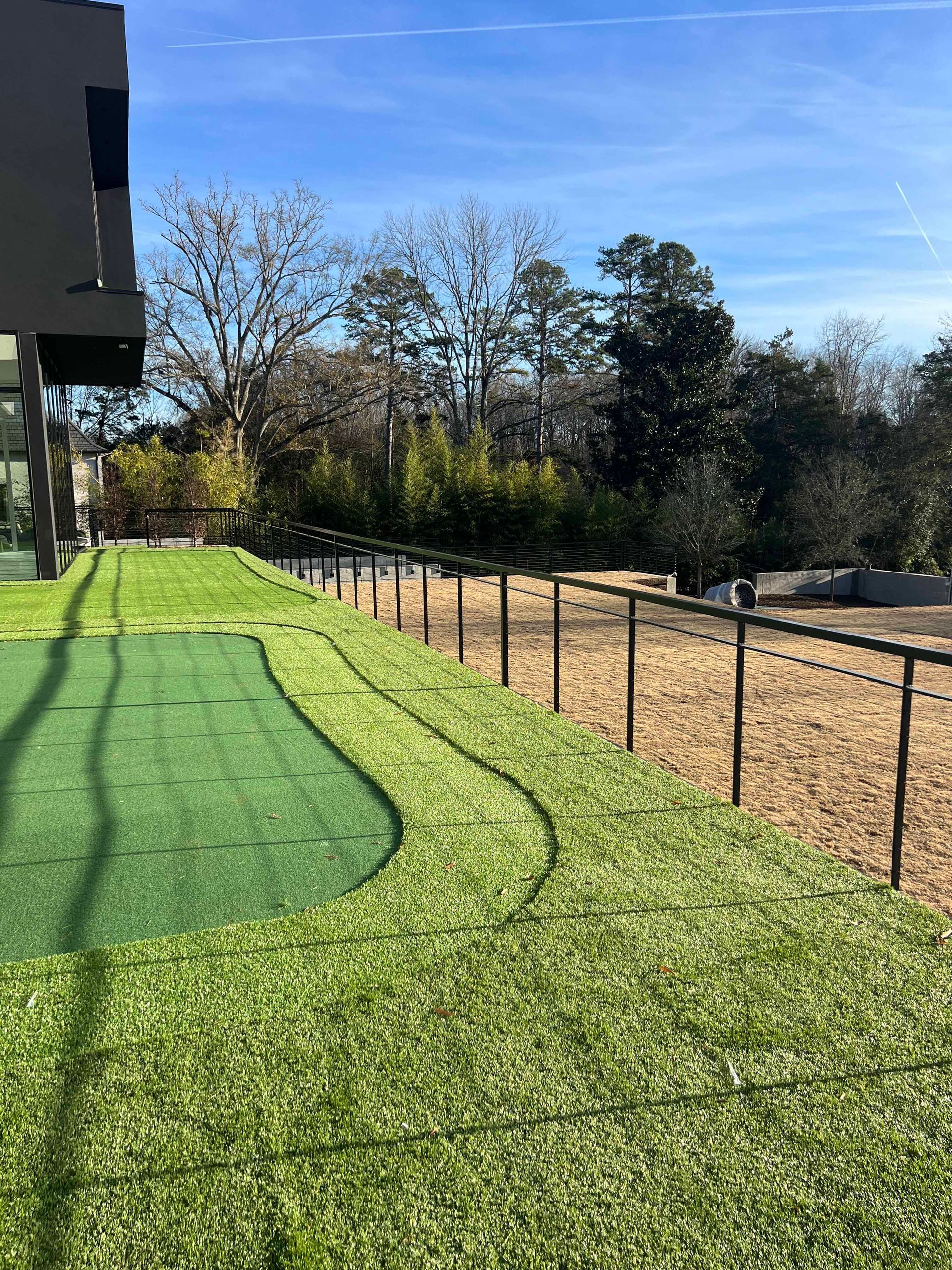 There is a golf course in the backyard of a house.