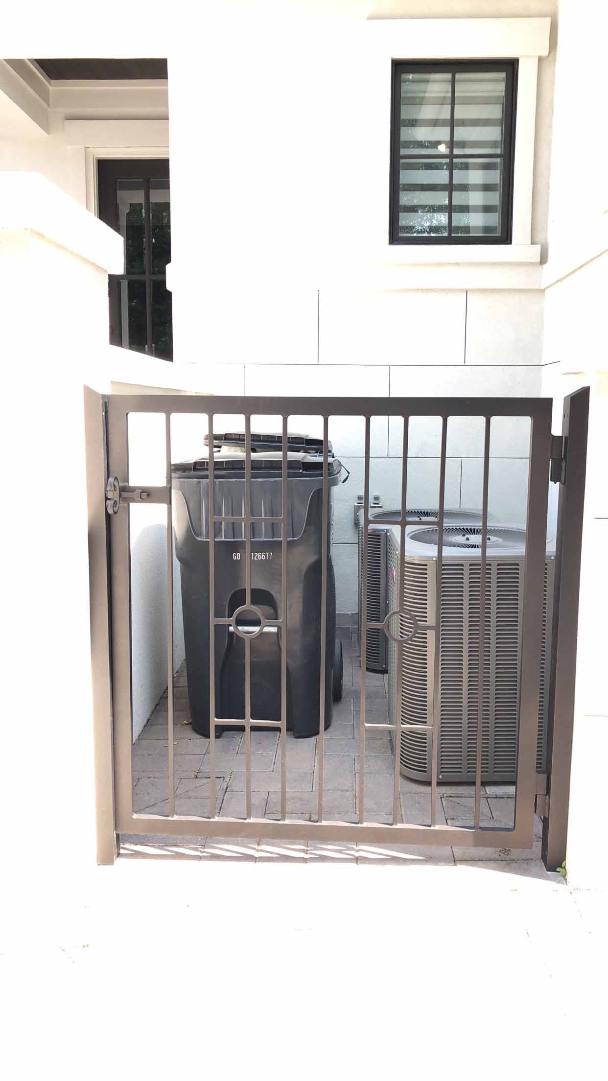 A trash can is behind a metal gate in a room.