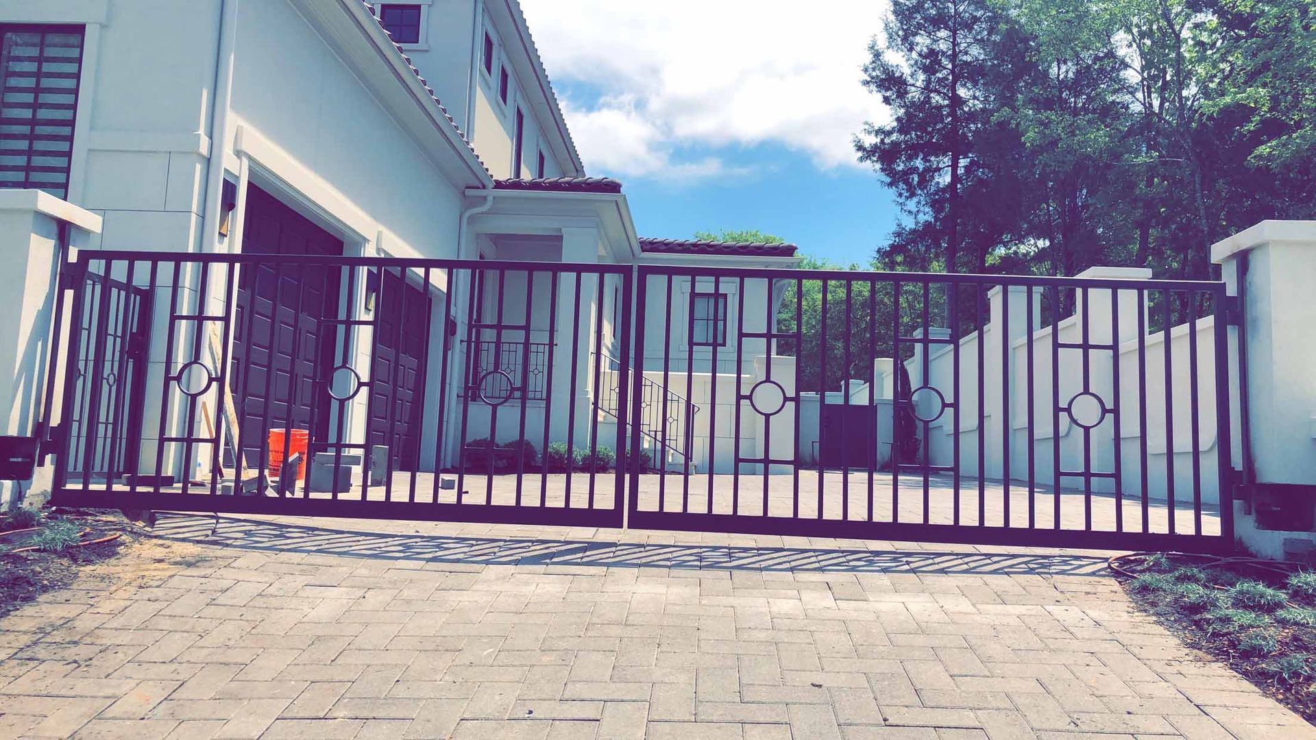 A sliding gate is open in front of a white house.