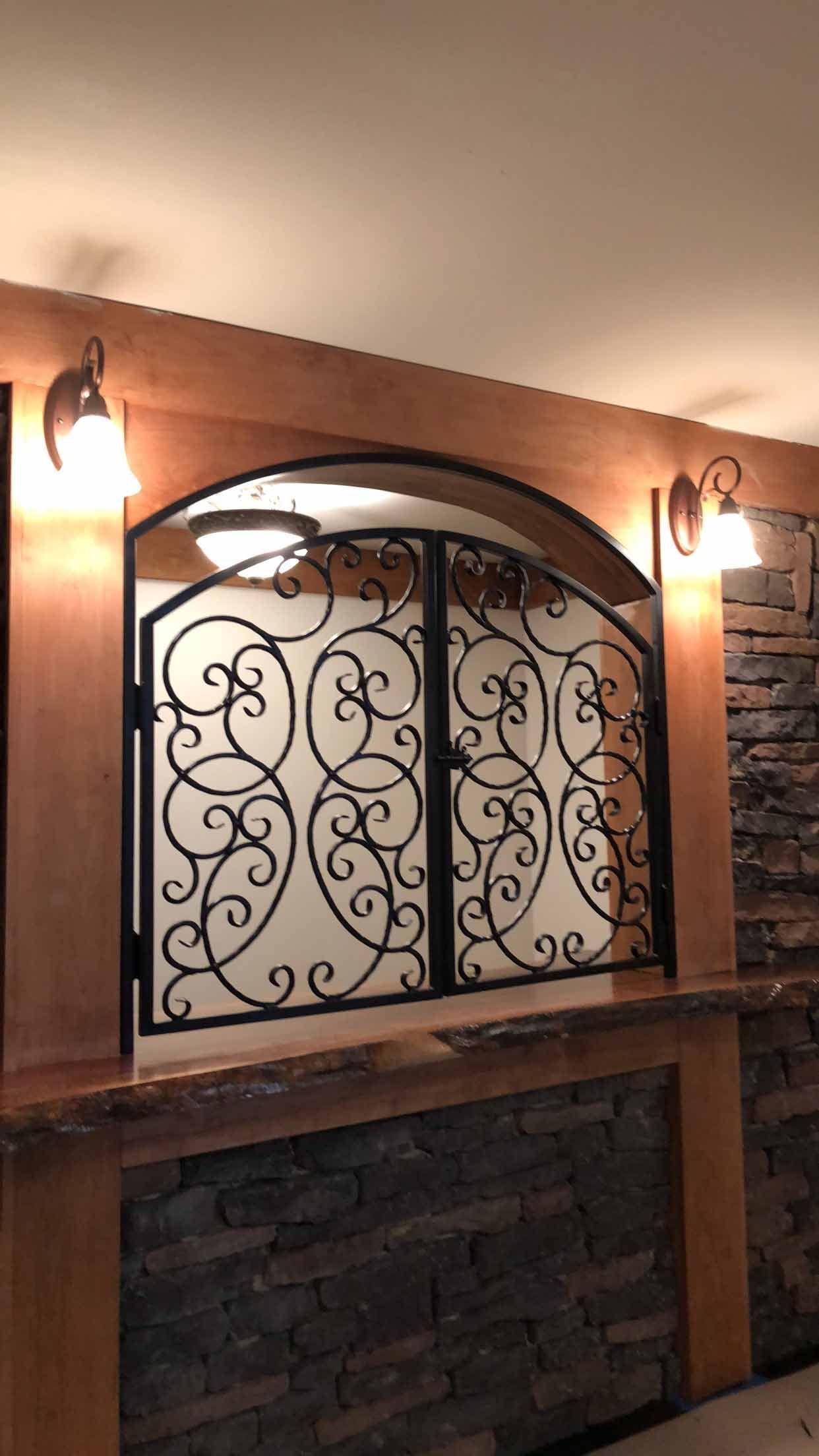 A room with a wrought iron window and a brick wall.