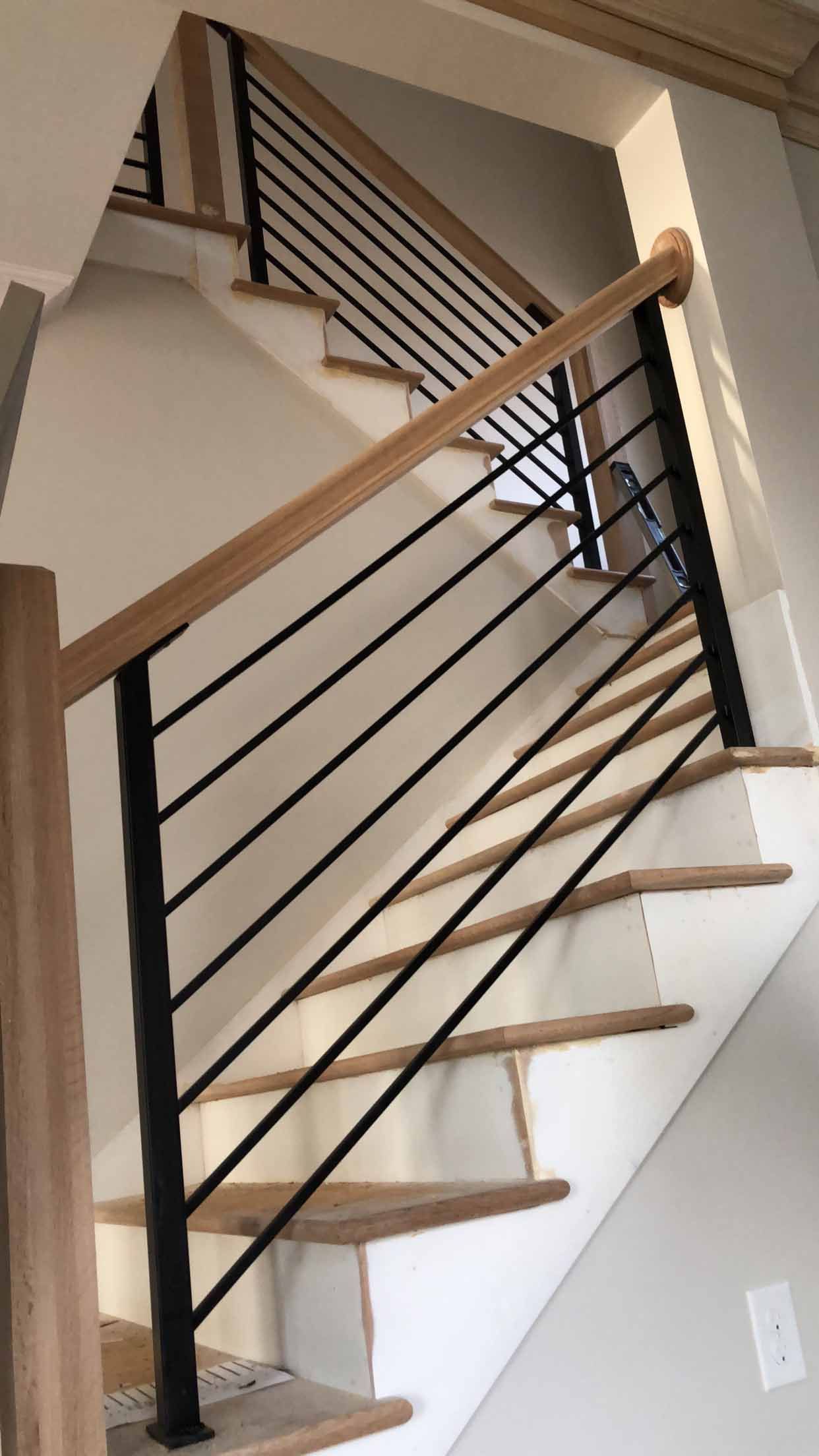 A staircase with wooden steps and a black railing.