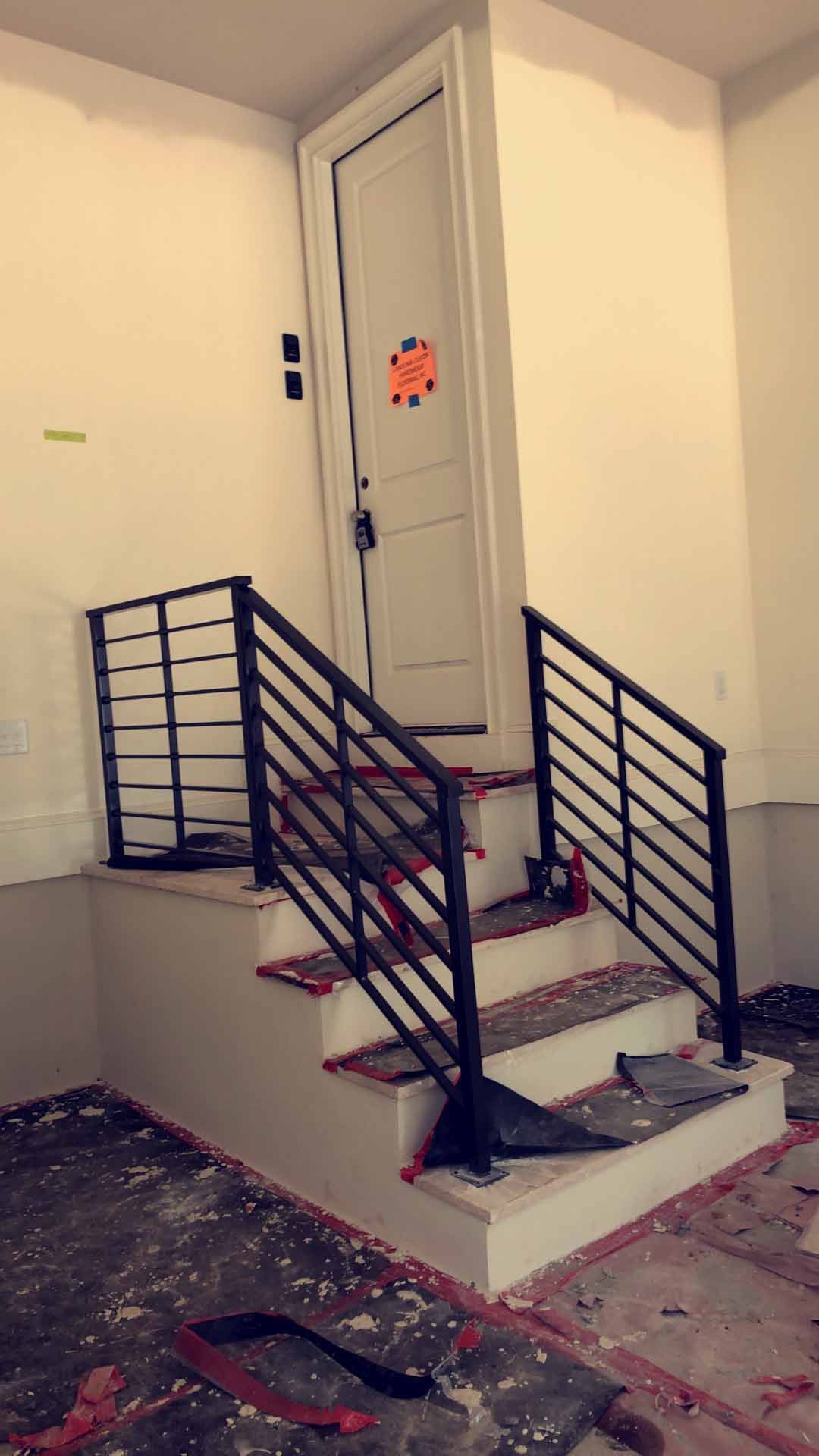 A staircase with a metal railing and a door in the background.