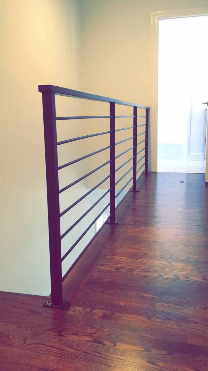 A hallway with a railing and a wooden floor