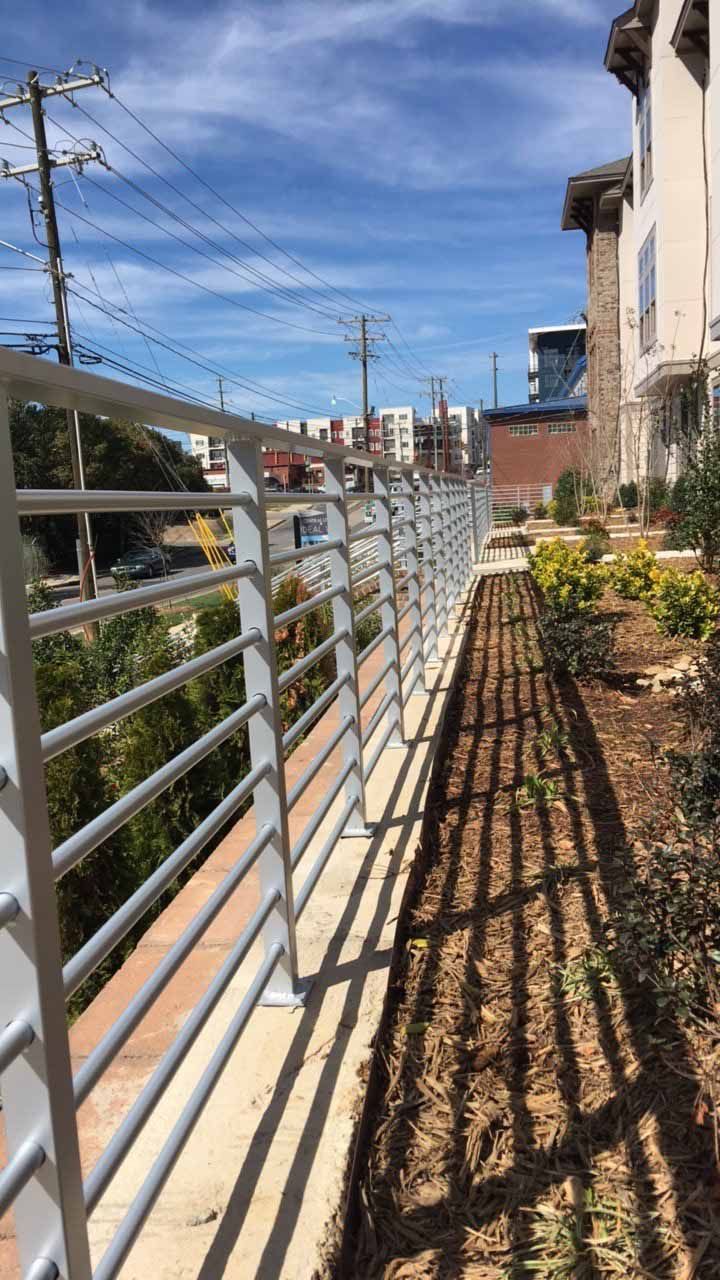 A metal fence along a sidewalk next to a building.