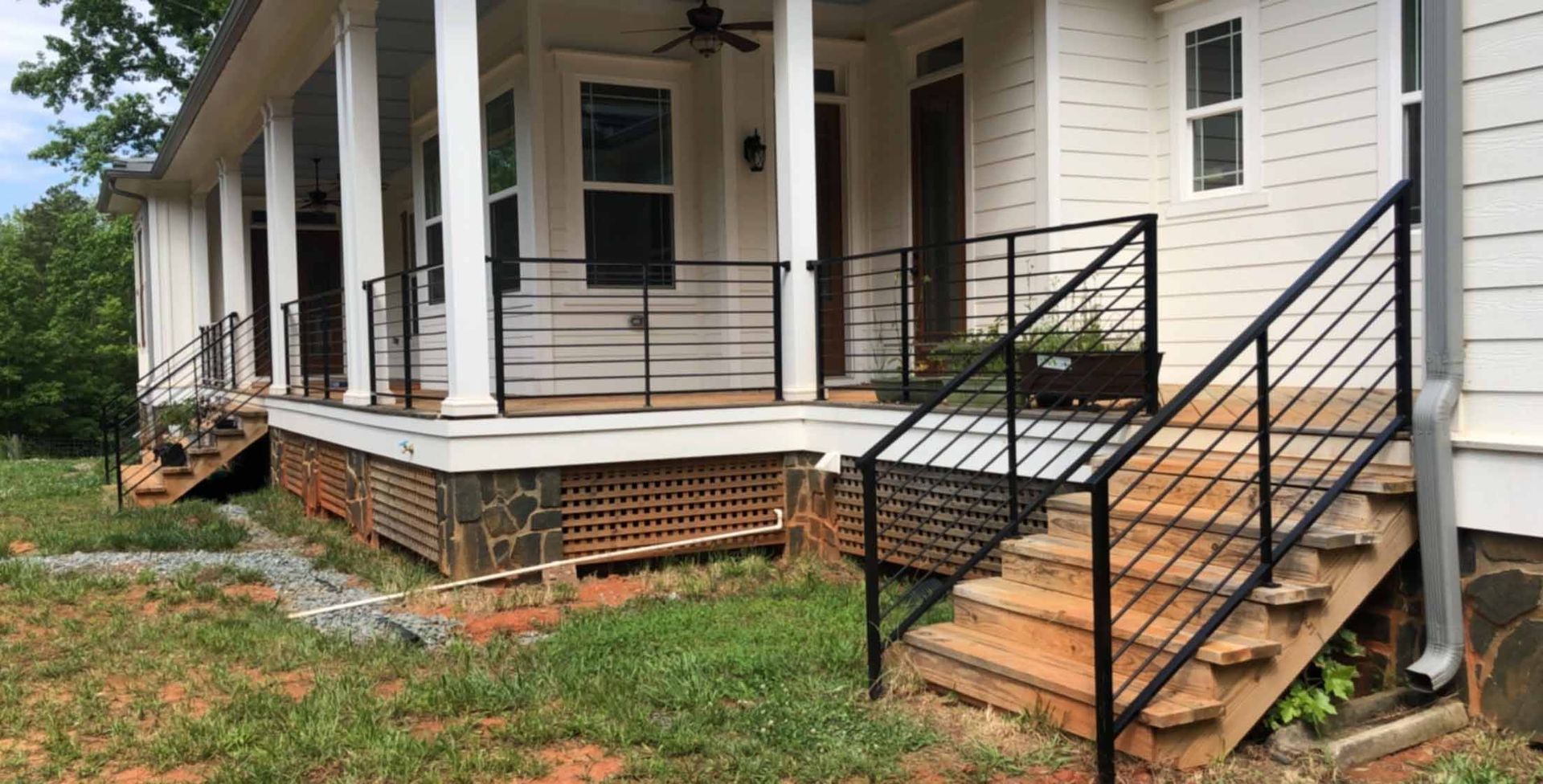 A white house with a porch and stairs with a black railing.