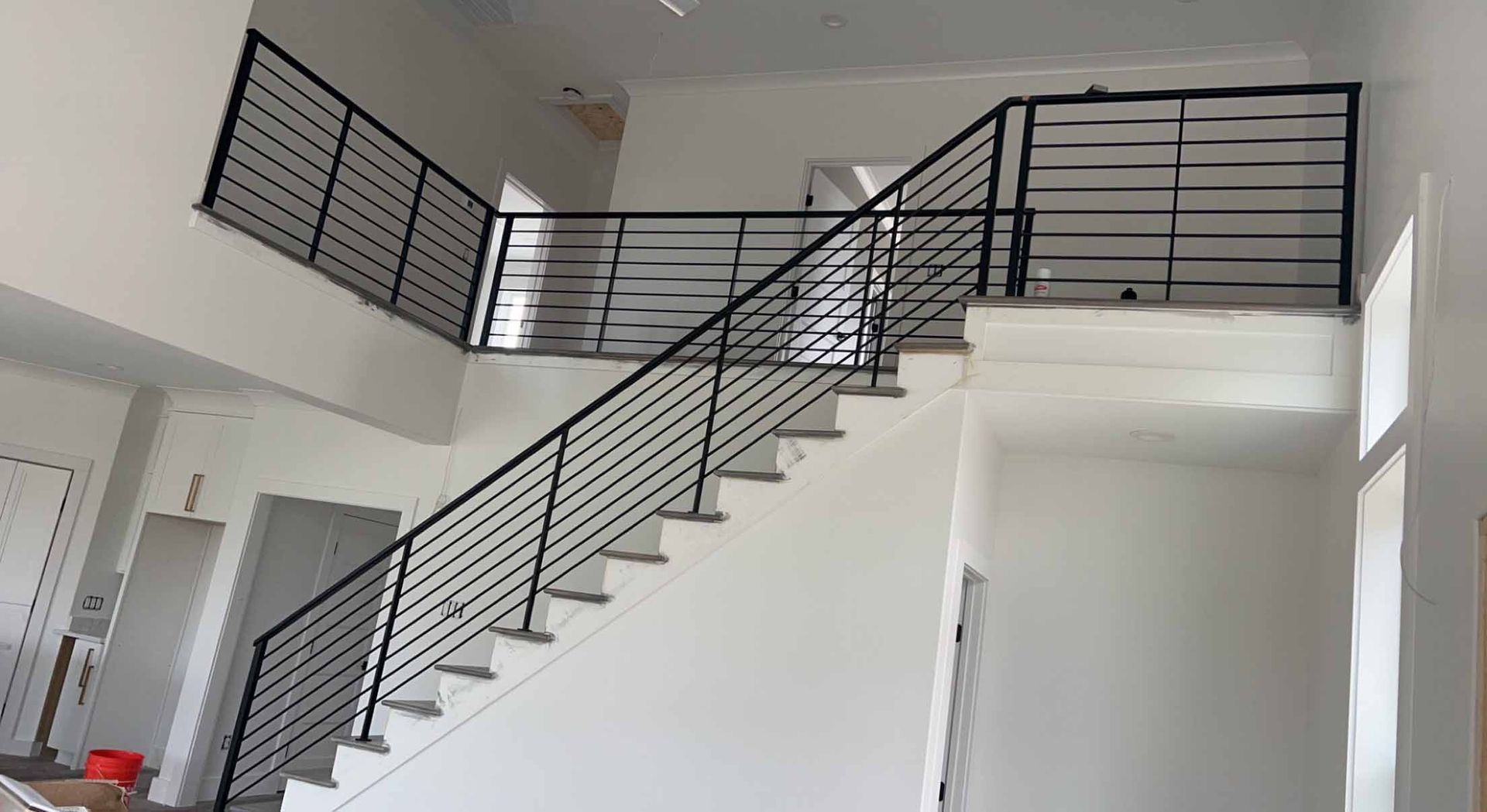 A staircase with a black railing is going up to the second floor of a house.