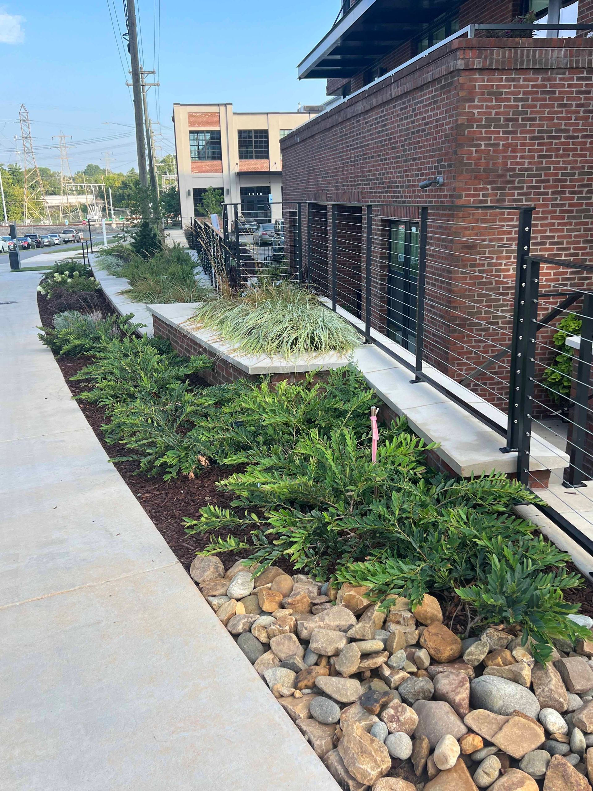 A brick building with a walkway surrounded by plants and rocks.