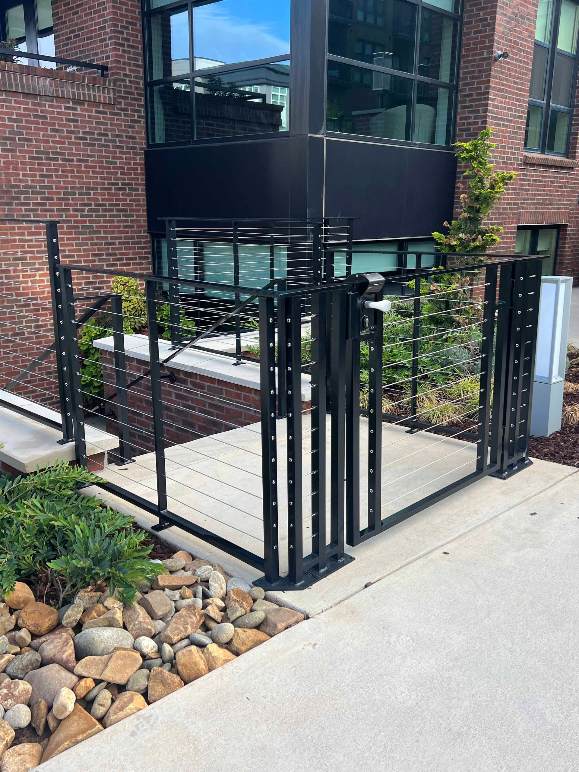A black fence is surrounding a brick building with a ramp.