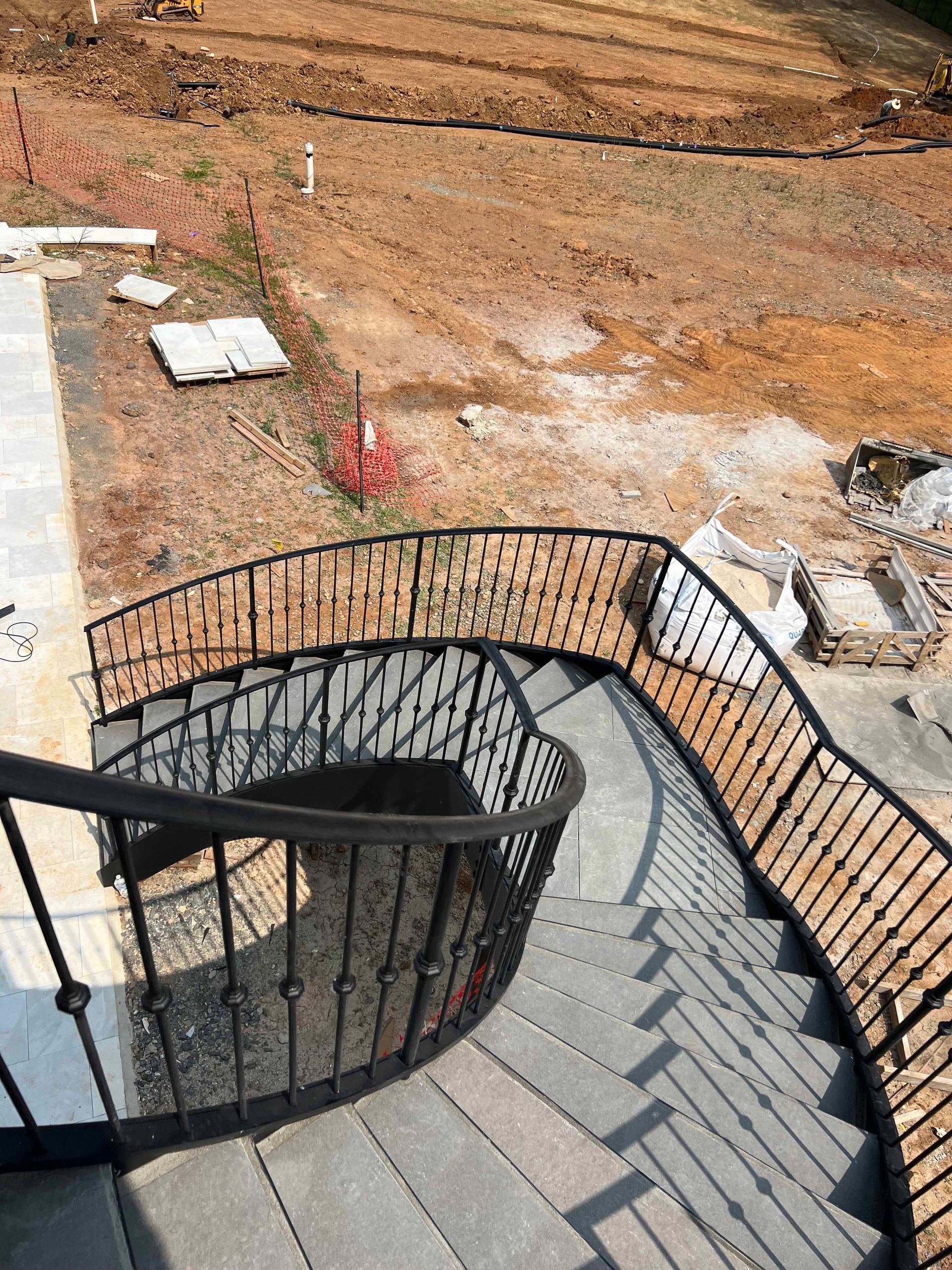 A spiral staircase with a wooden railing is going up to a building under construction.