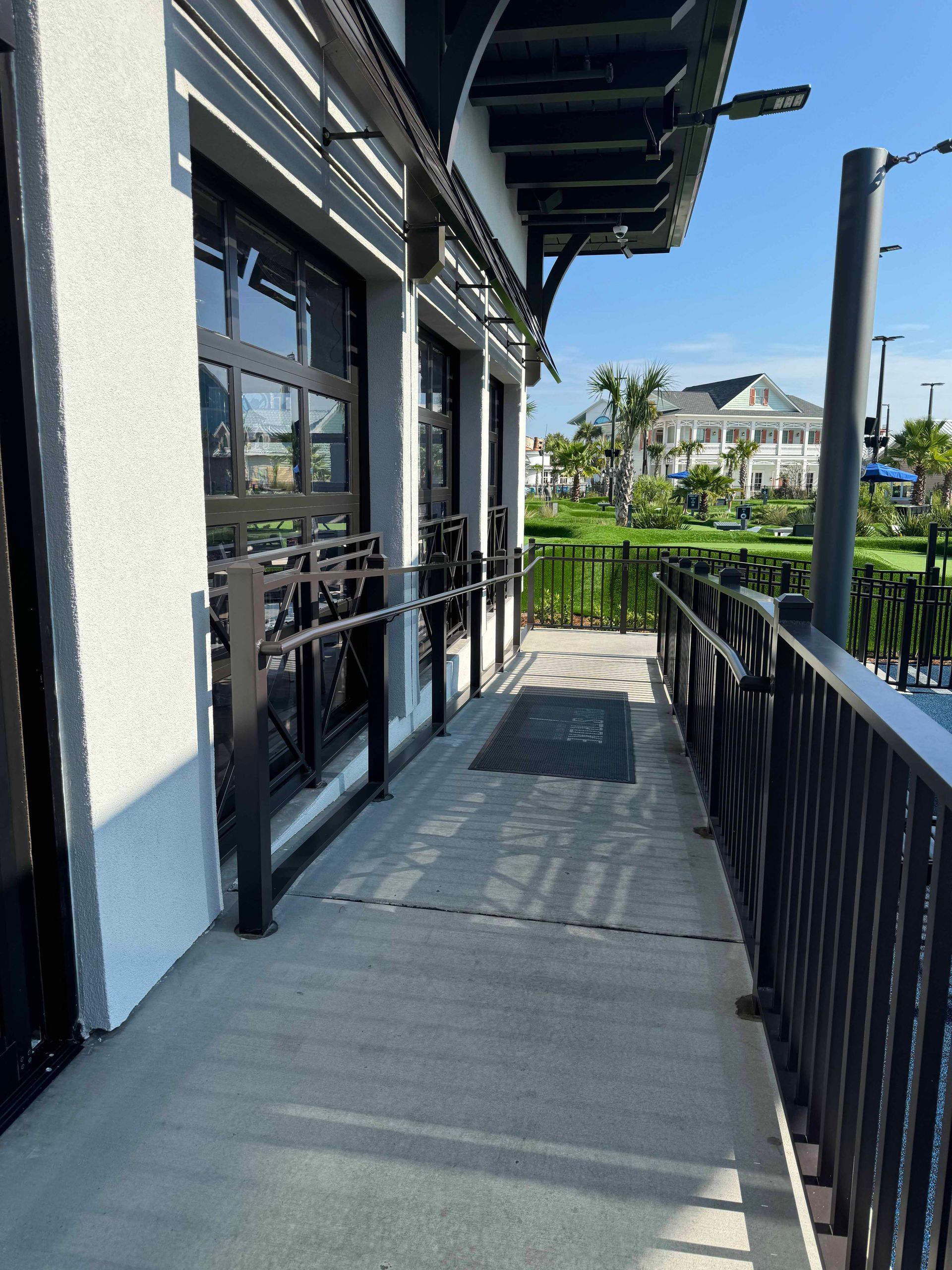 A concrete walkway leading to a building with a railing