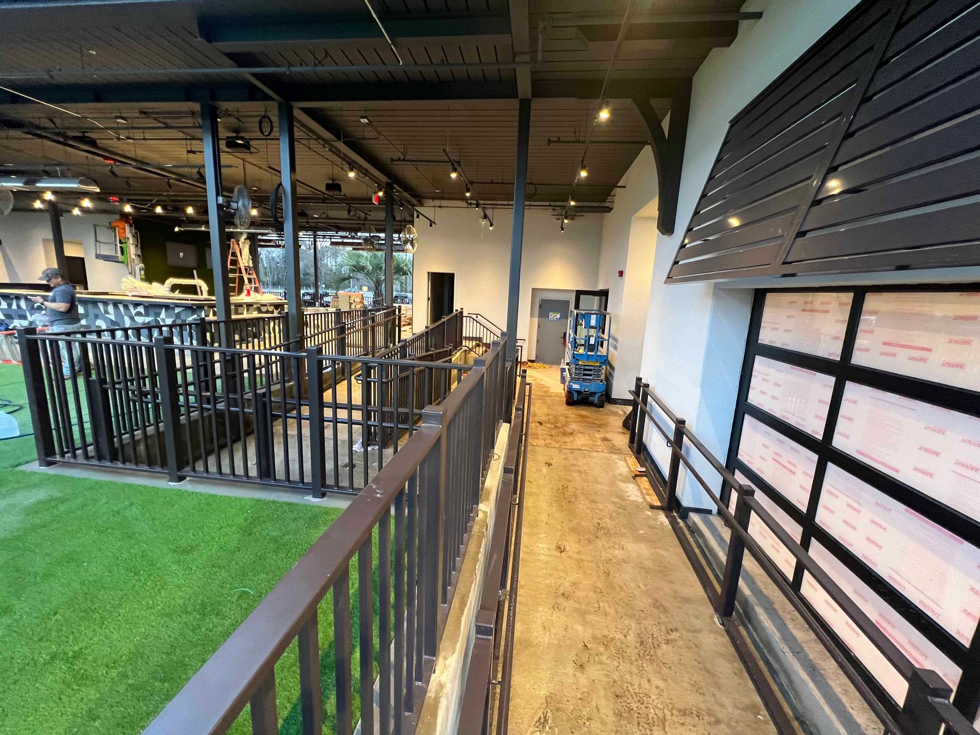 A long hallway with a railing leading to a large room.