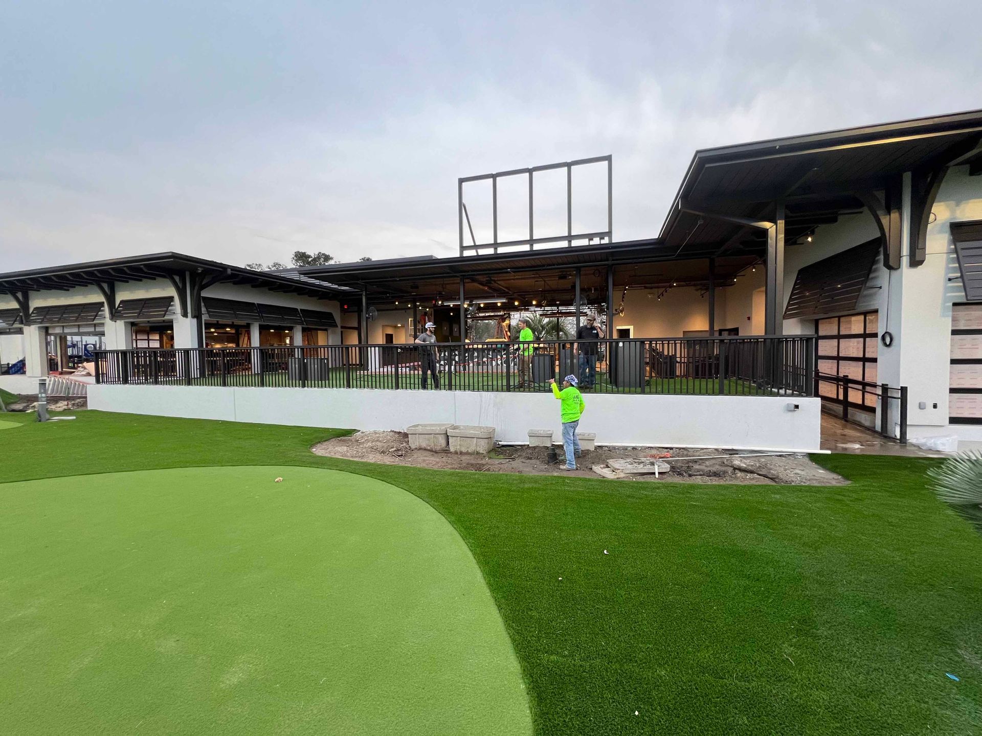 A group of people are working on a golf course in front of a building.
