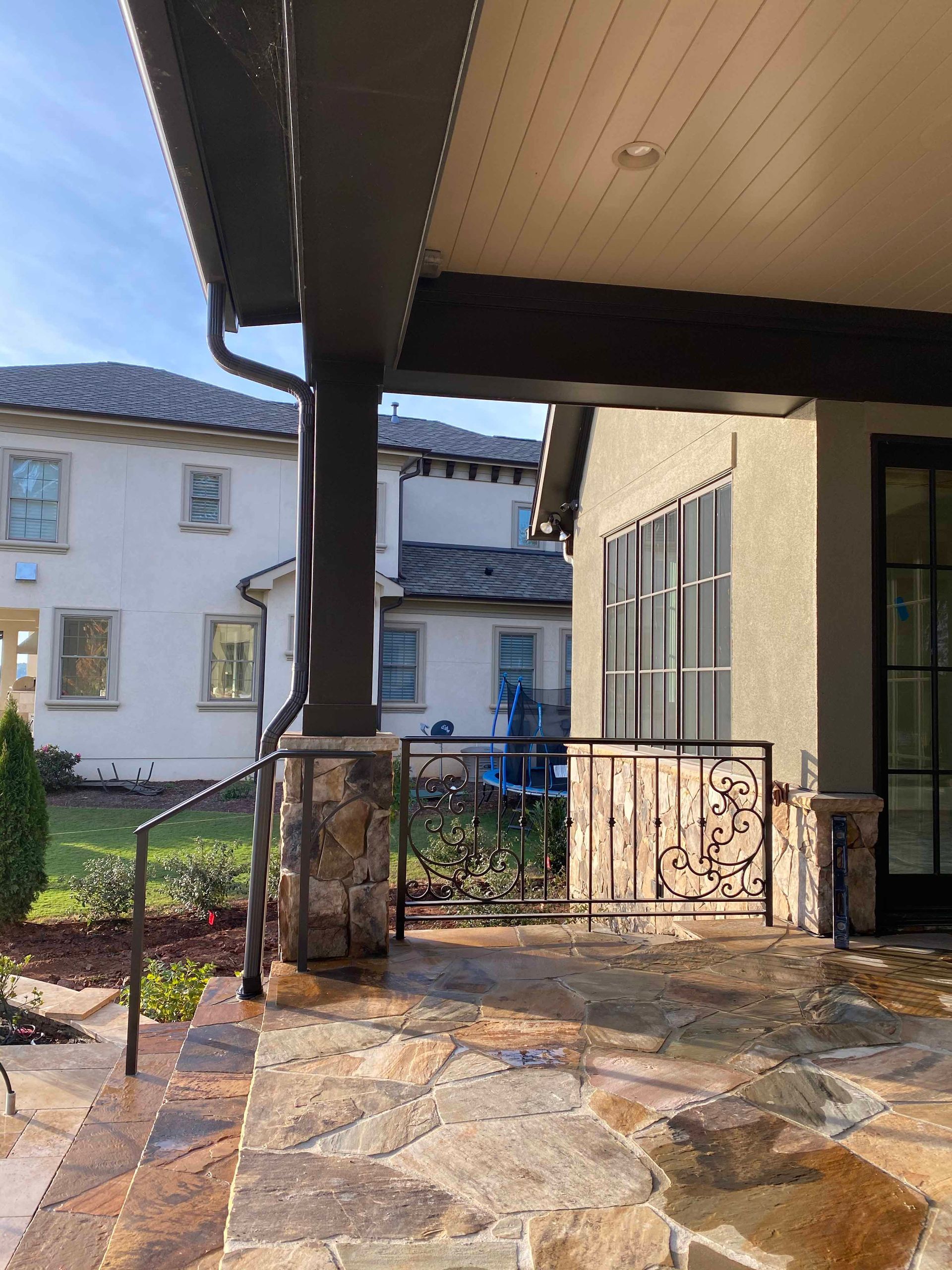 A stone patio with a railing and a house in the background.