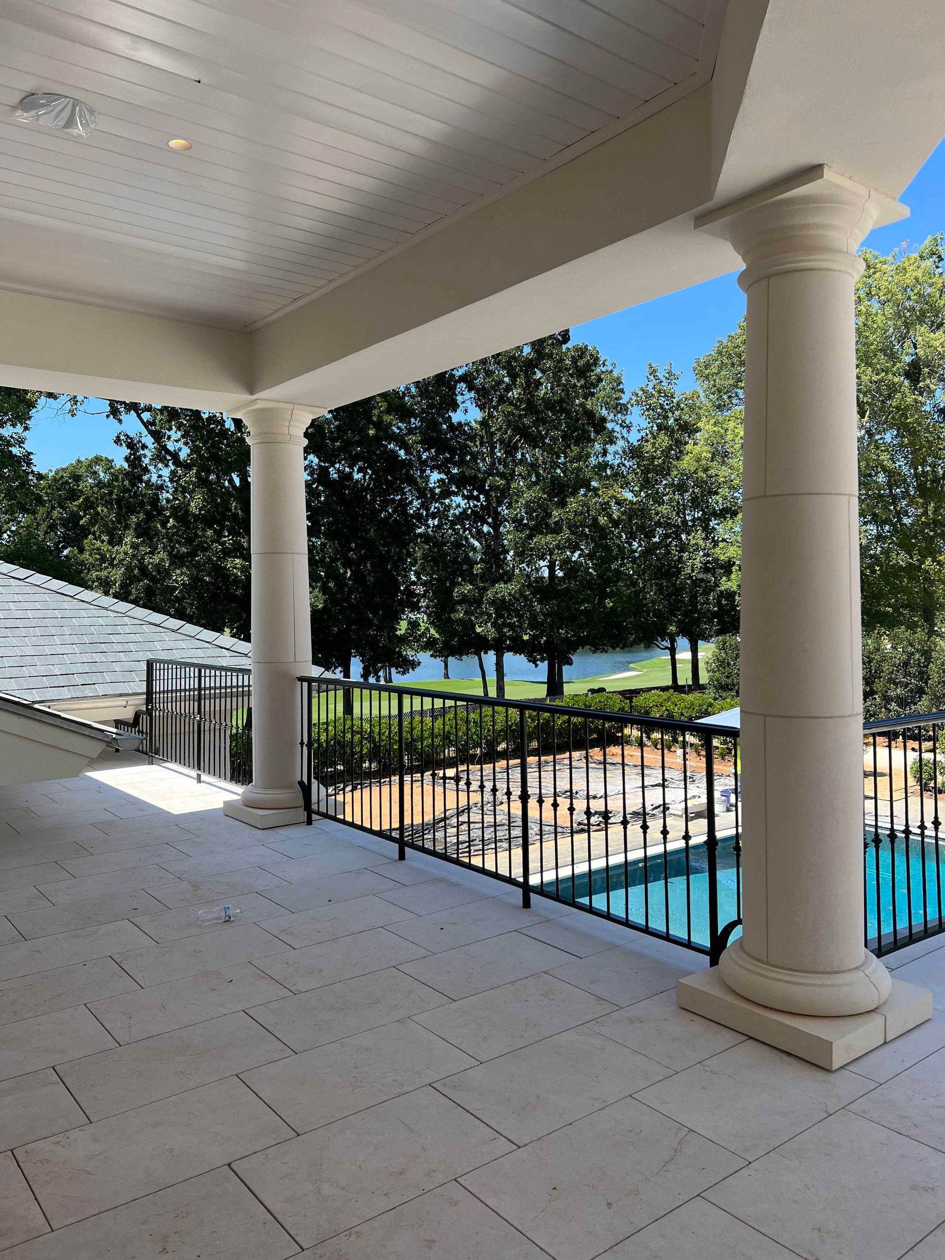 A balcony overlooking a swimming pool with trees in the background