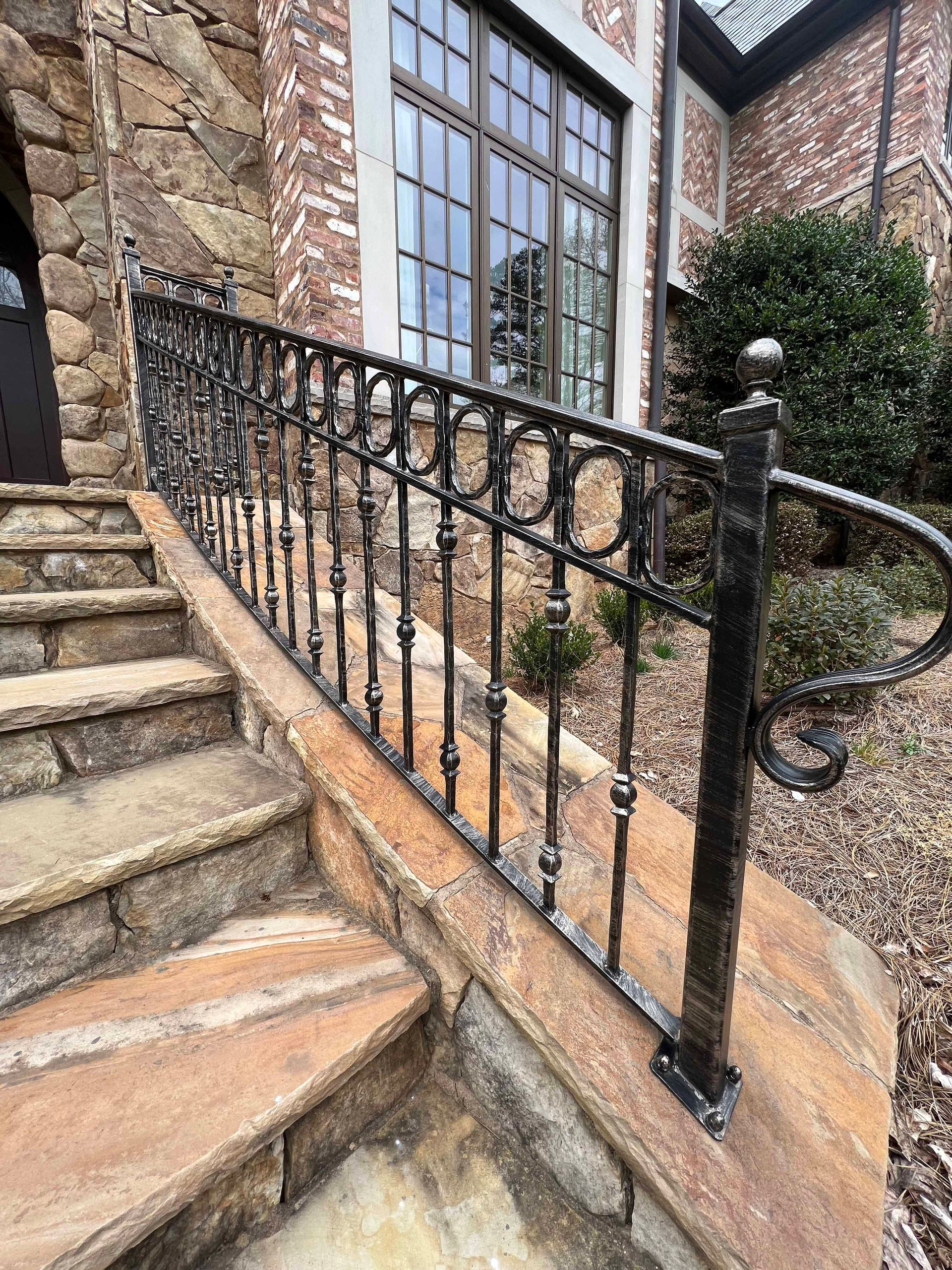 A wrought iron railing on a set of stairs leading up to a house.