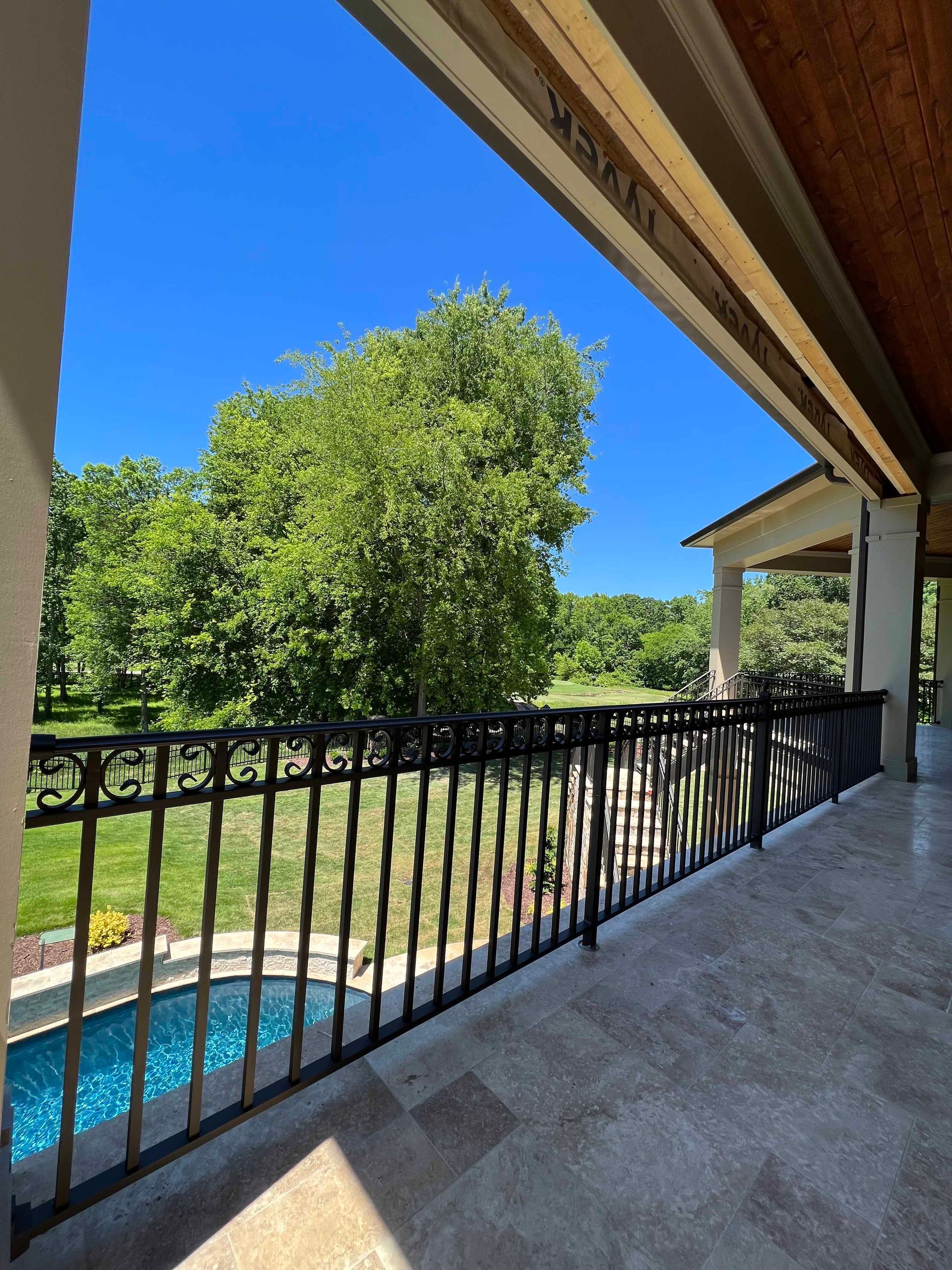 A balcony overlooking a swimming pool with trees in the background