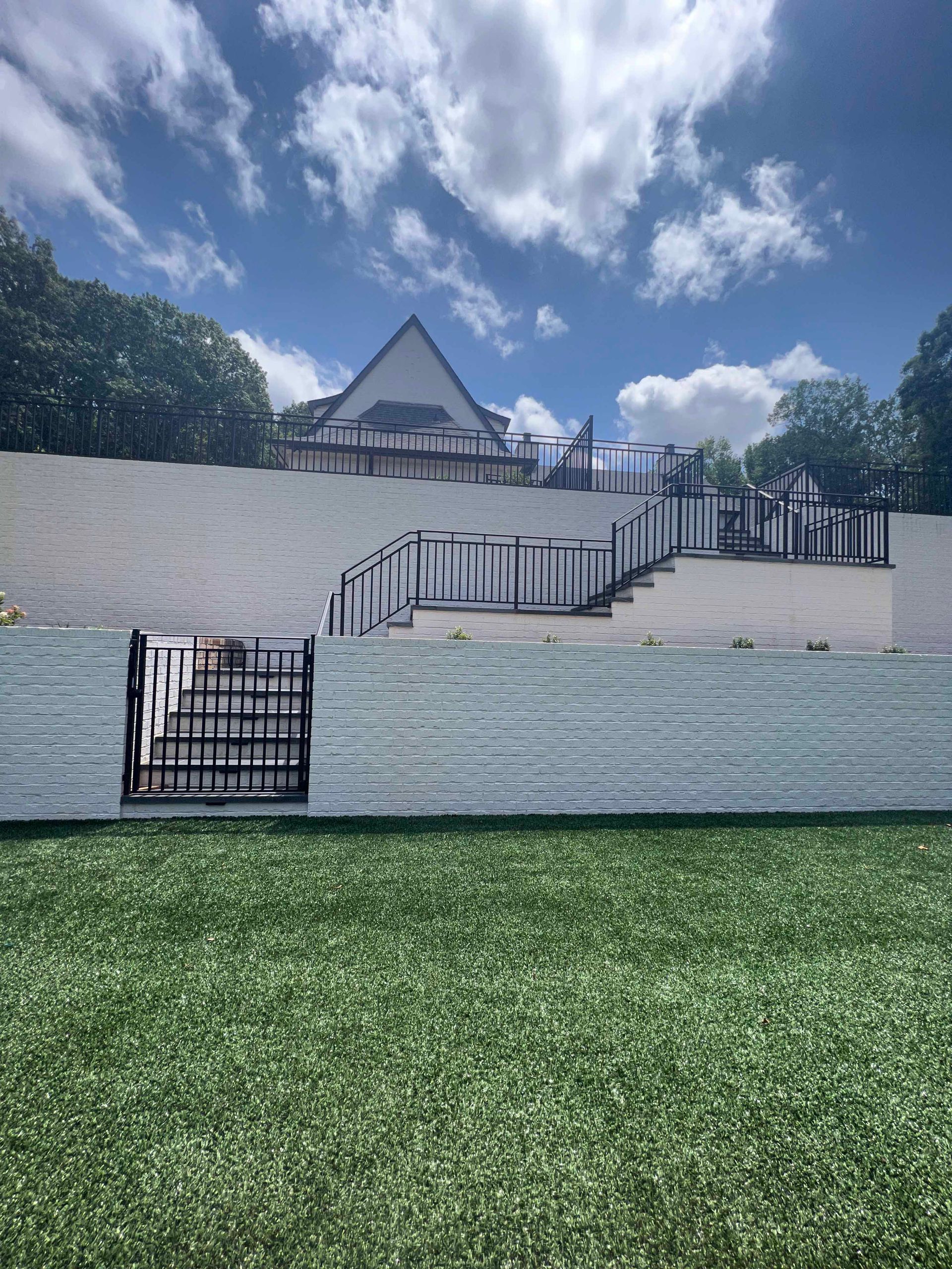A fence with stairs leading up to a house in the background.