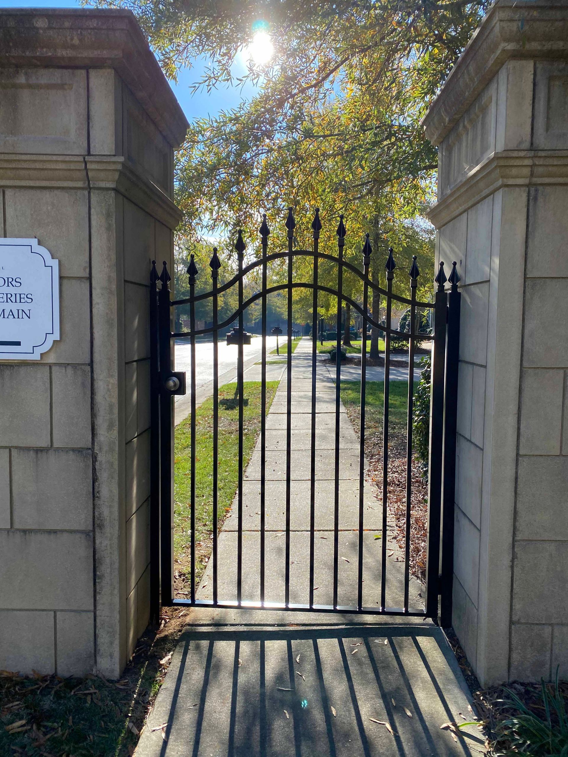 A wrought iron gate is leading to a park