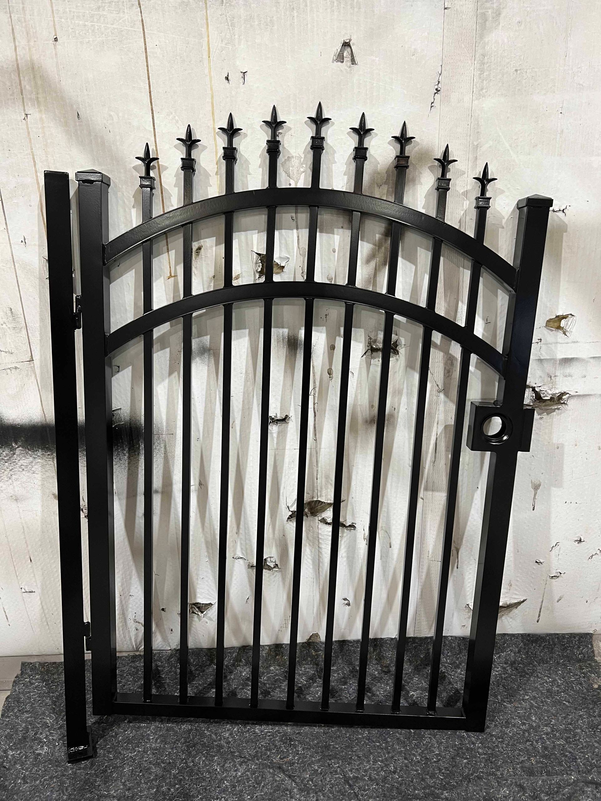 A black wrought iron gate is sitting in front of a white wall.