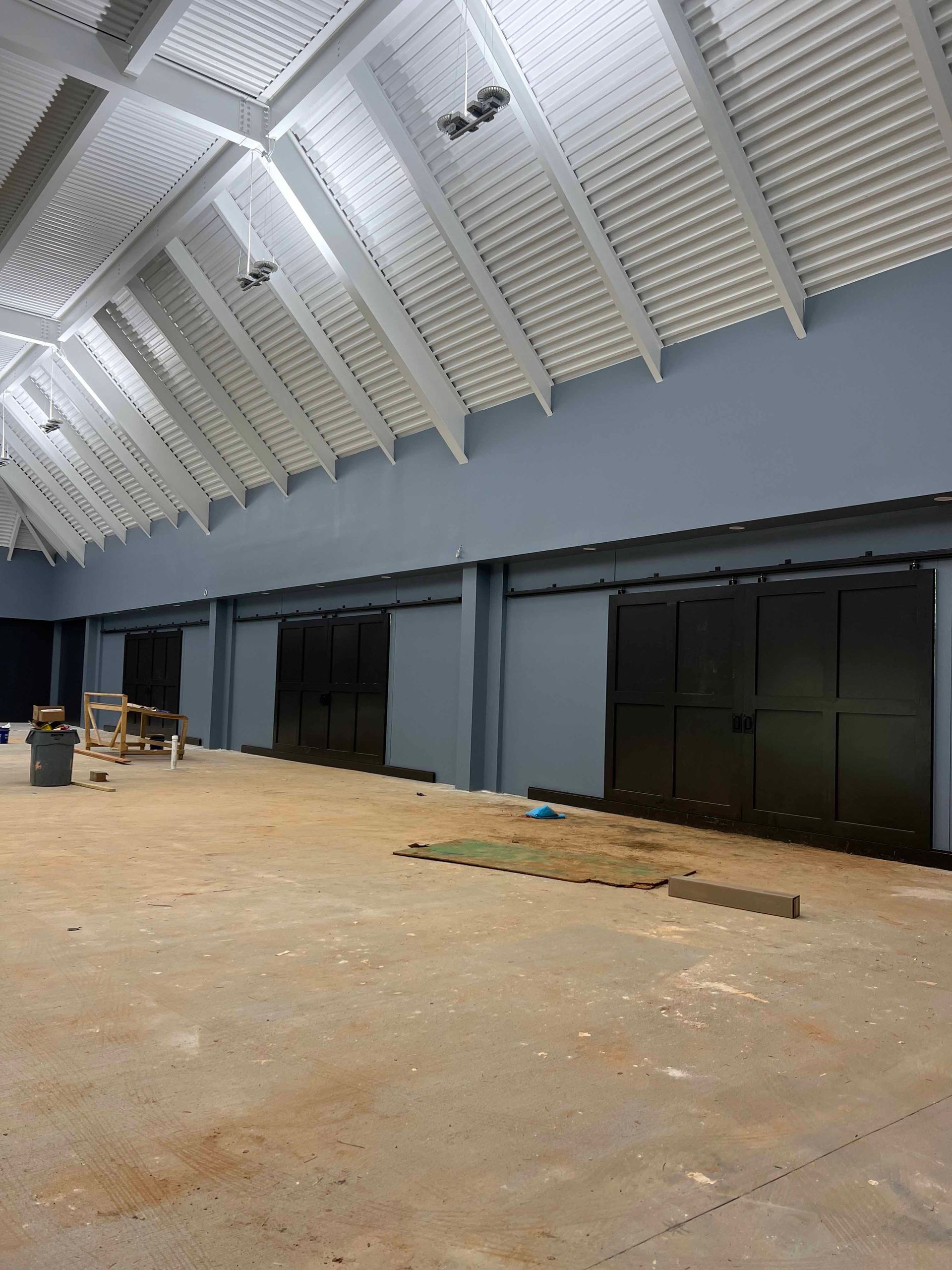 A large empty room with a white ceiling and black doors