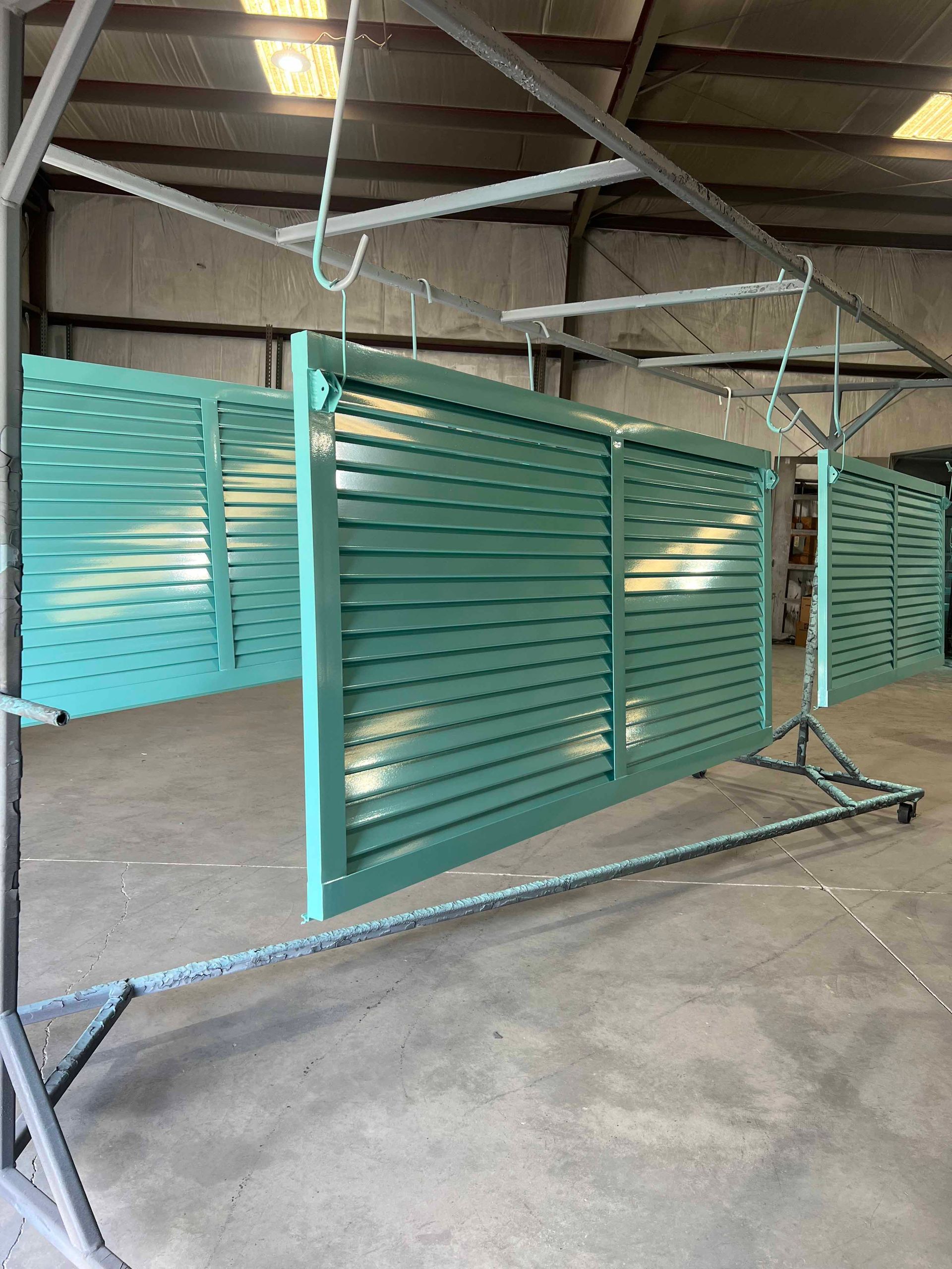A green fence is being painted in a warehouse.