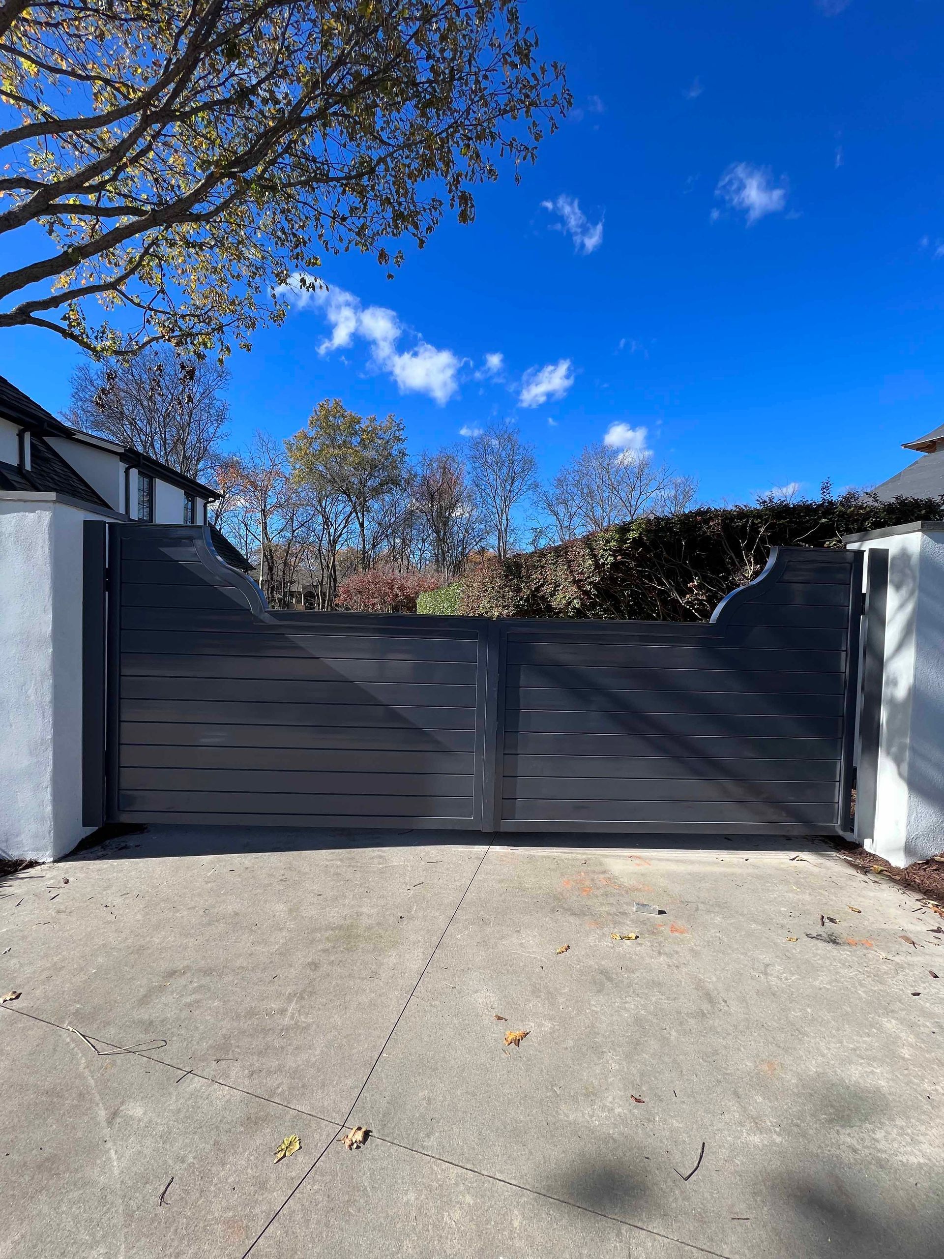 A black gate is sitting in the middle of a driveway.