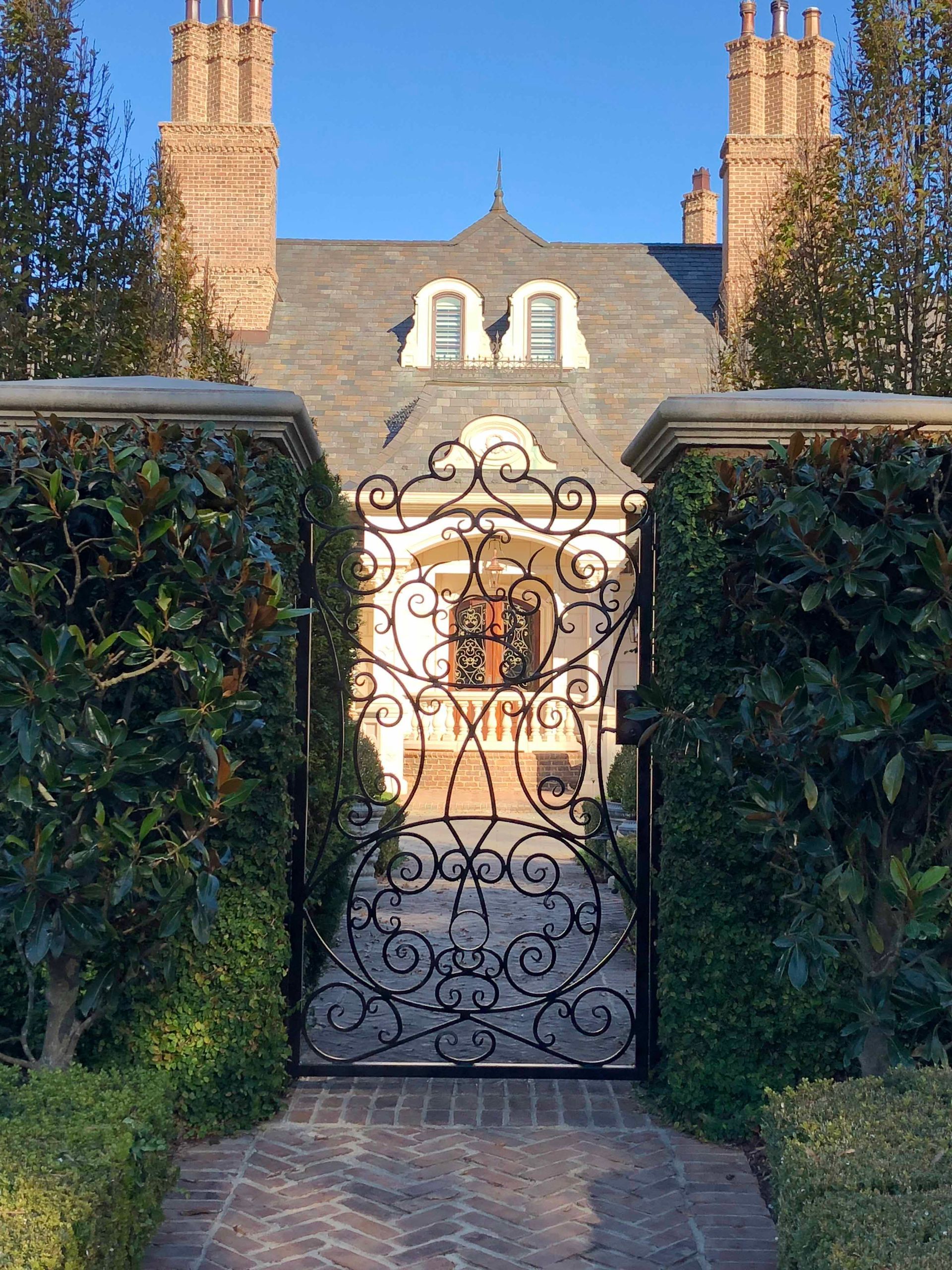 A wrought iron gate leads to a large house.