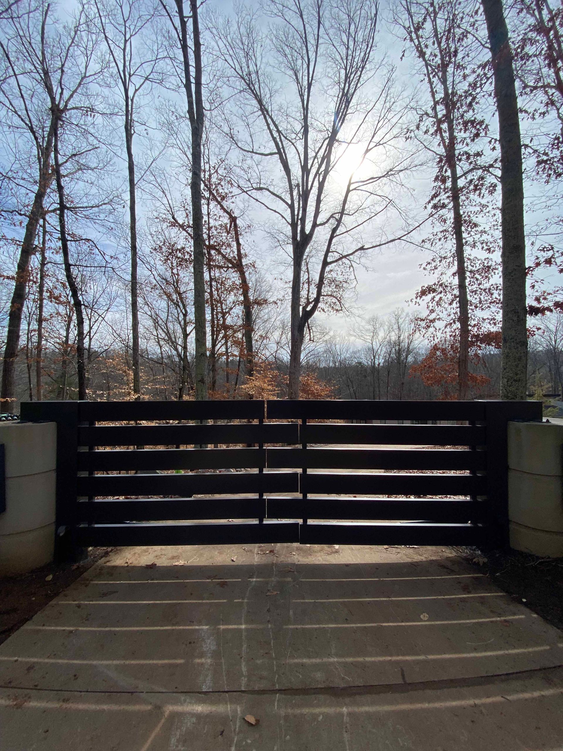 A fence with trees in the background and the sun shining through it
