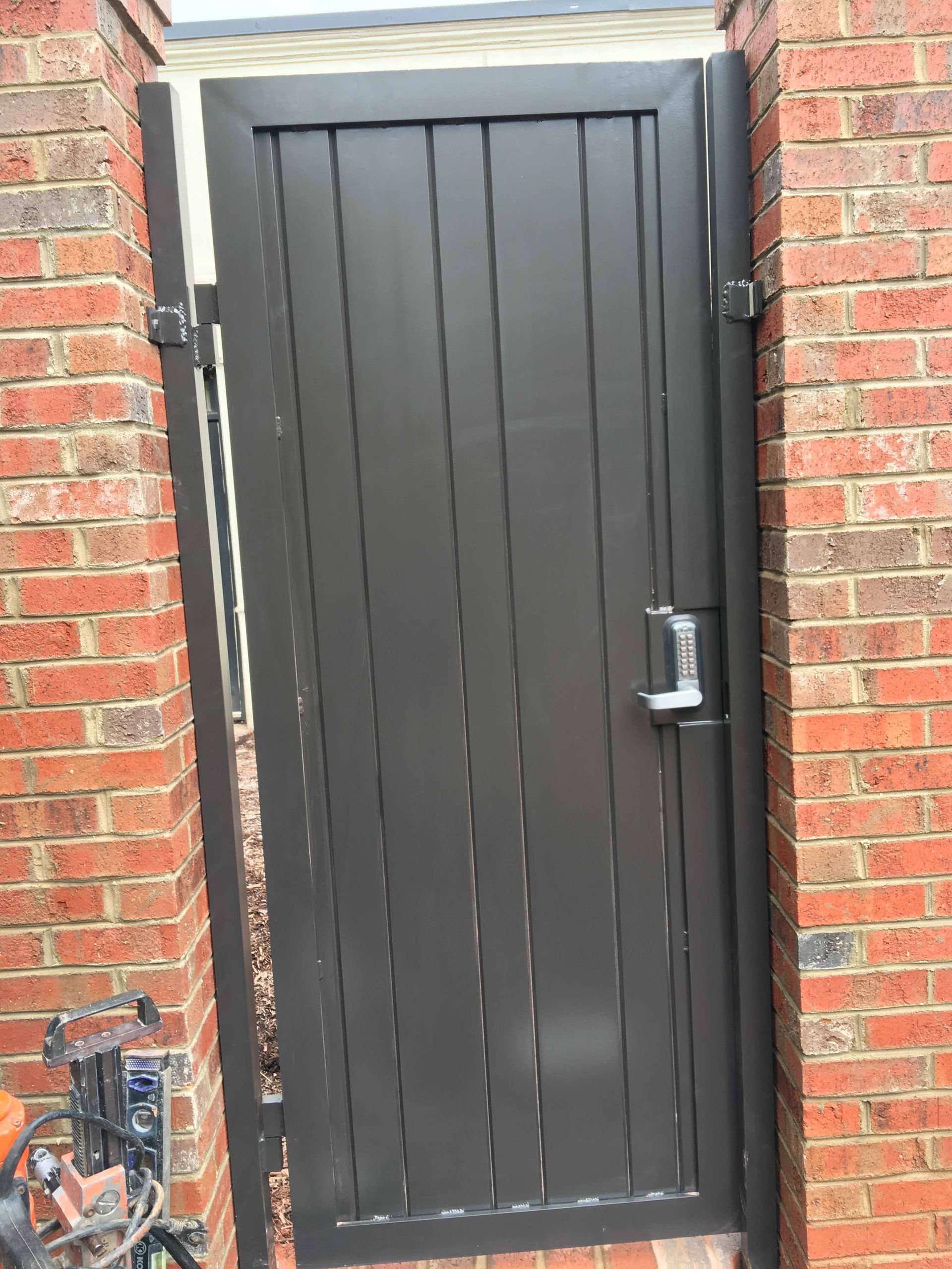 A black gate is sitting on the side of a brick building.