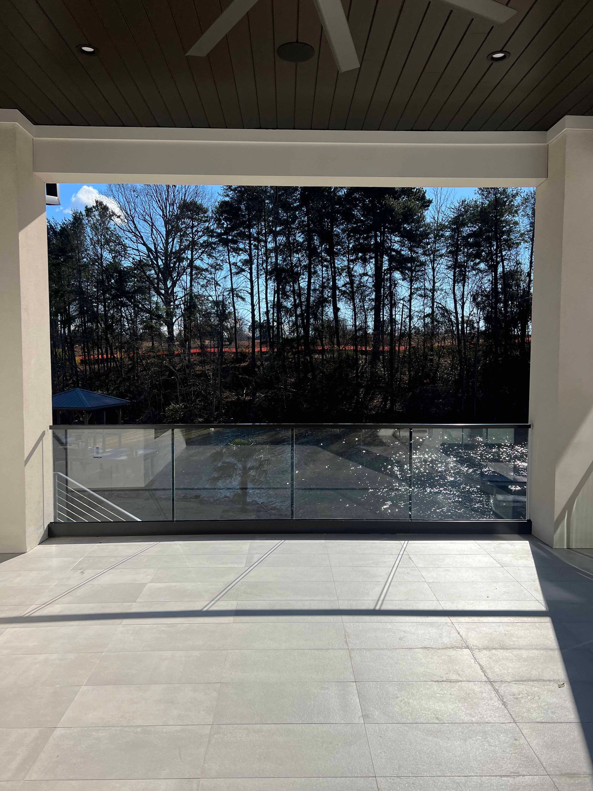 A balcony with a view of trees and a ceiling fan.