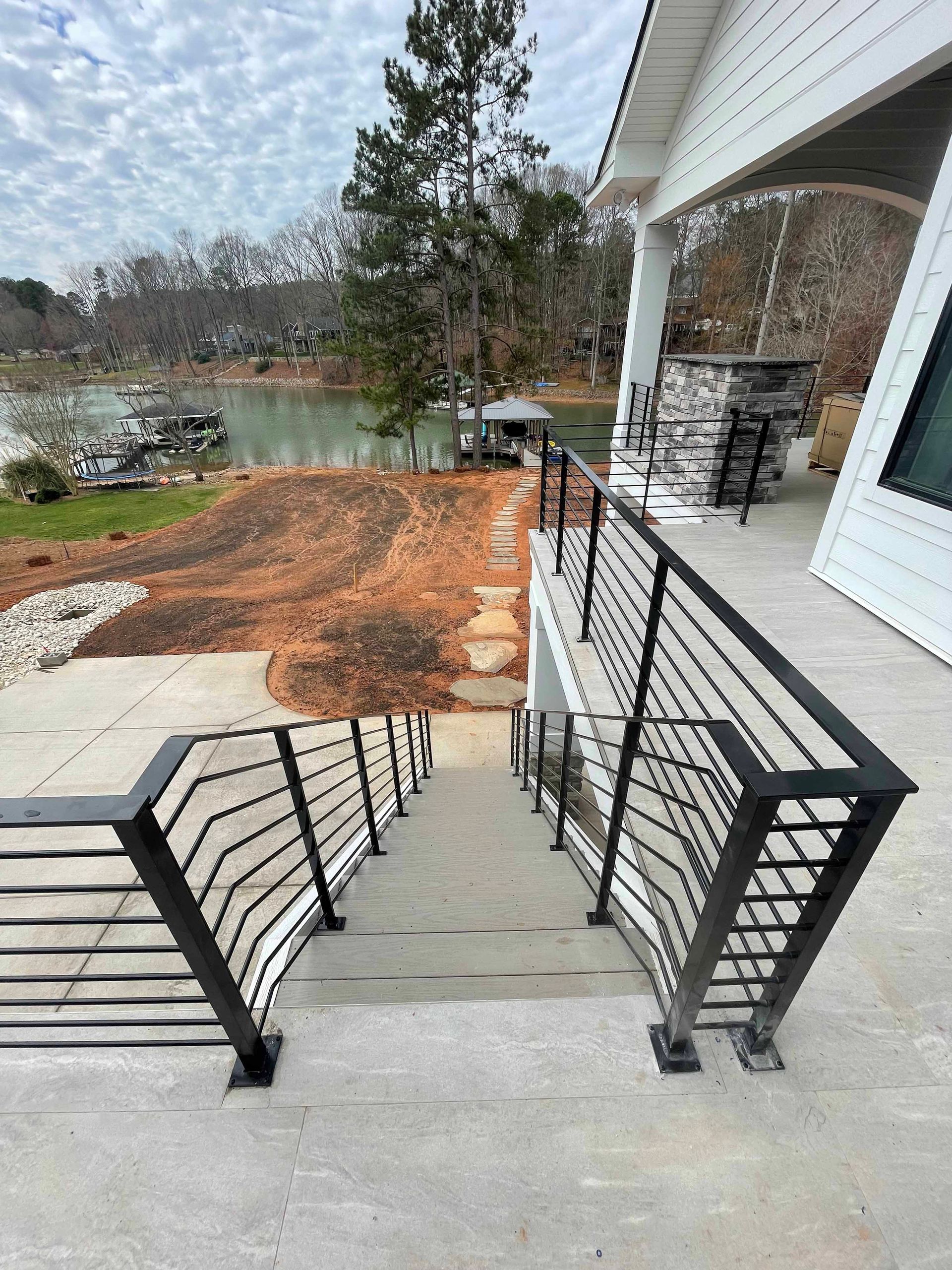 A set of stairs leading up to a deck with a railing and a view of a lake.