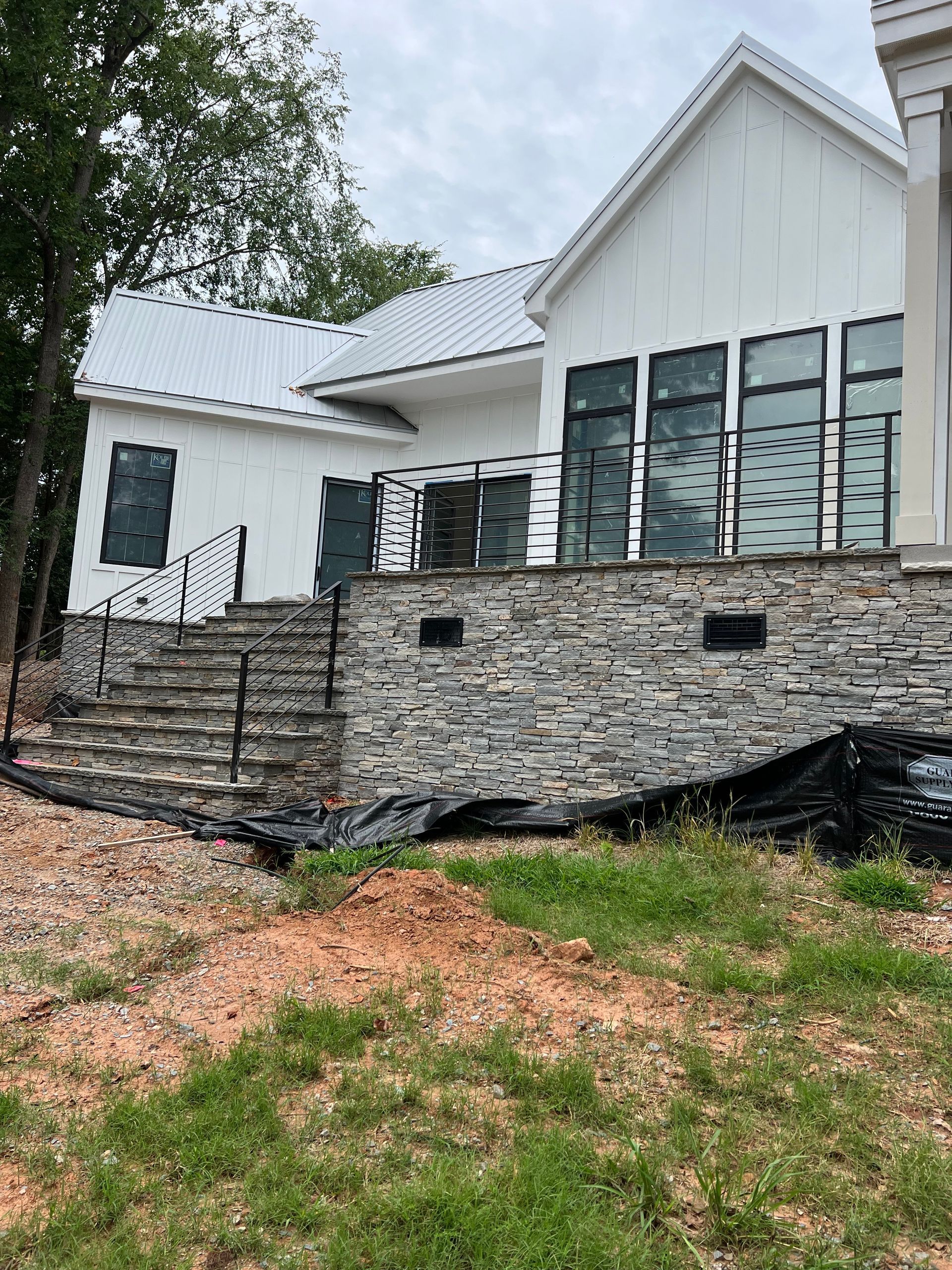 A white house with a stone wall and stairs in front of it.