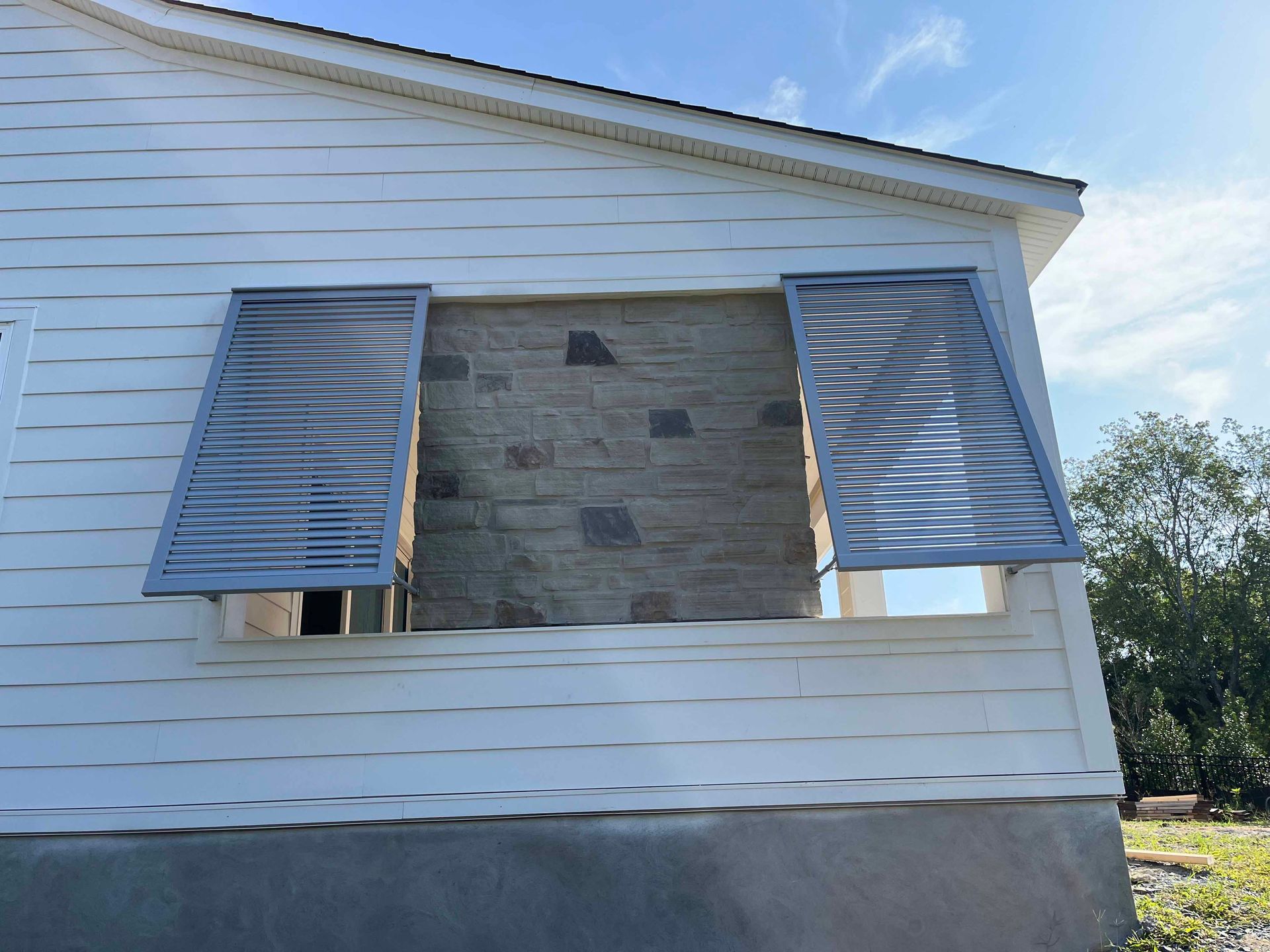 A white house with a window with shutters on it.