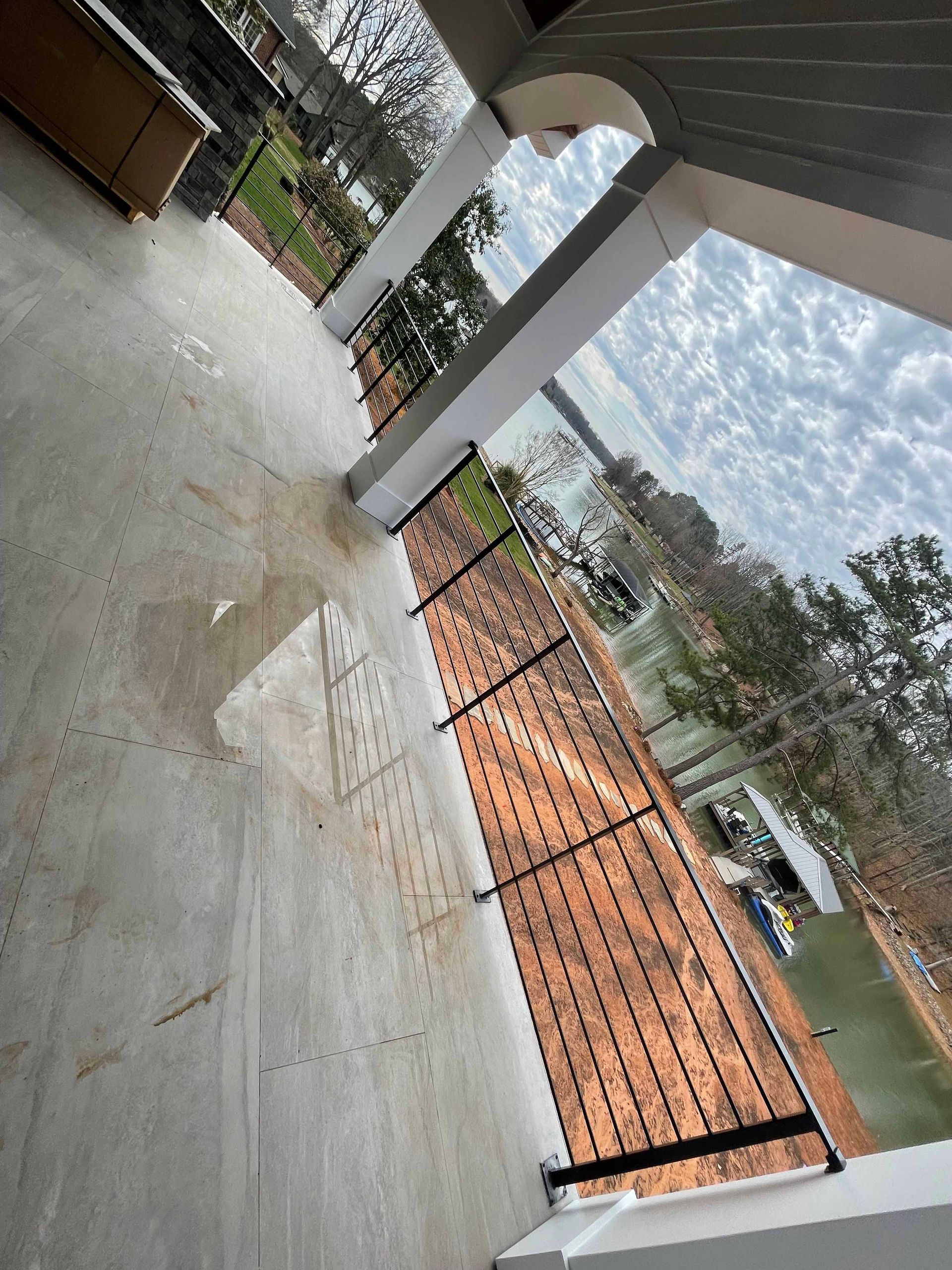 A balcony with a wrought iron railing overlooking a lake.