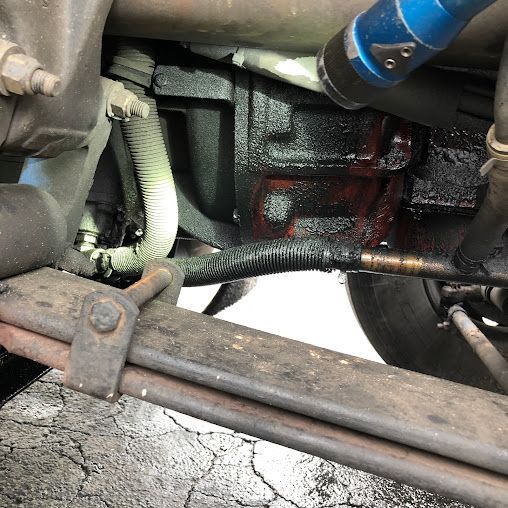 A close up of the underside of a car with a hose attached to it.