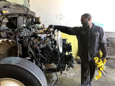 A man is working on a truck engine in a garage.