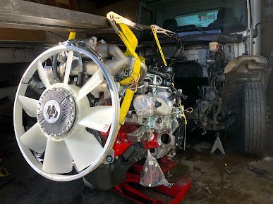A red and white engine with a fan attached to it is sitting on a lift.