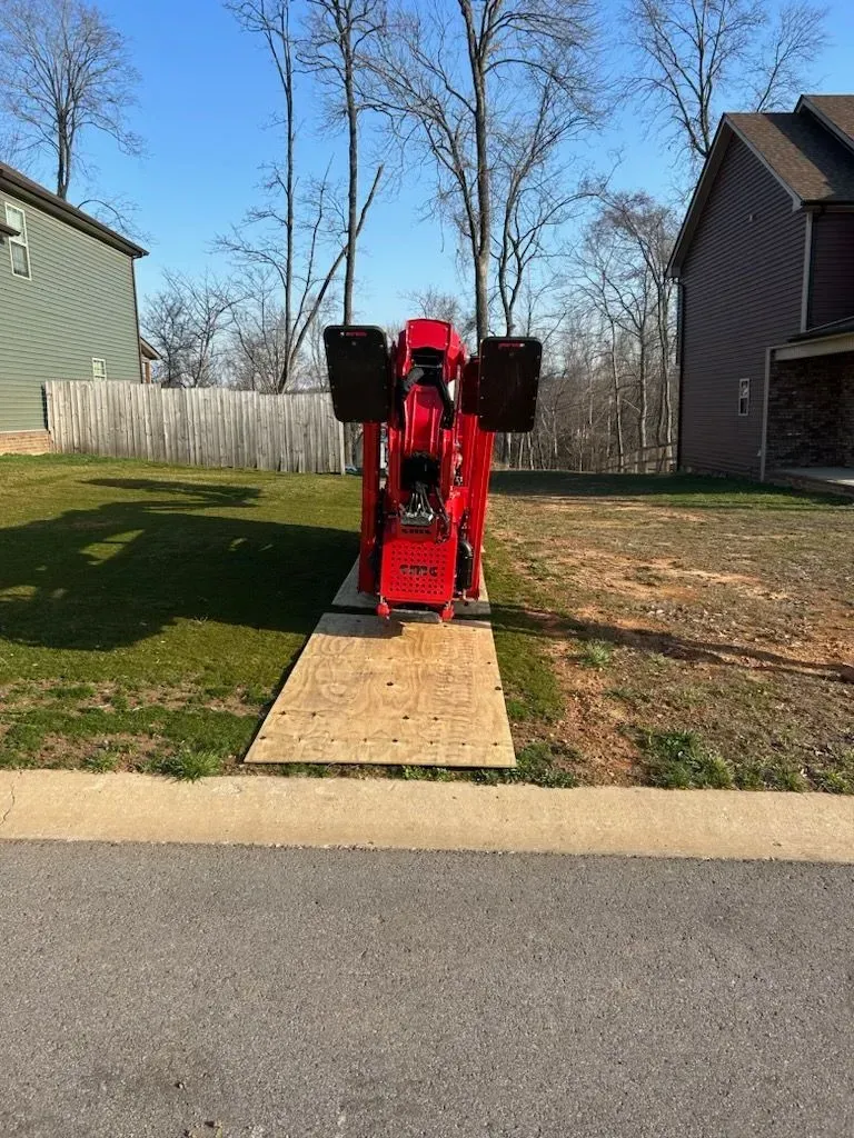 Red construction equipment on wooden platform in front yard.