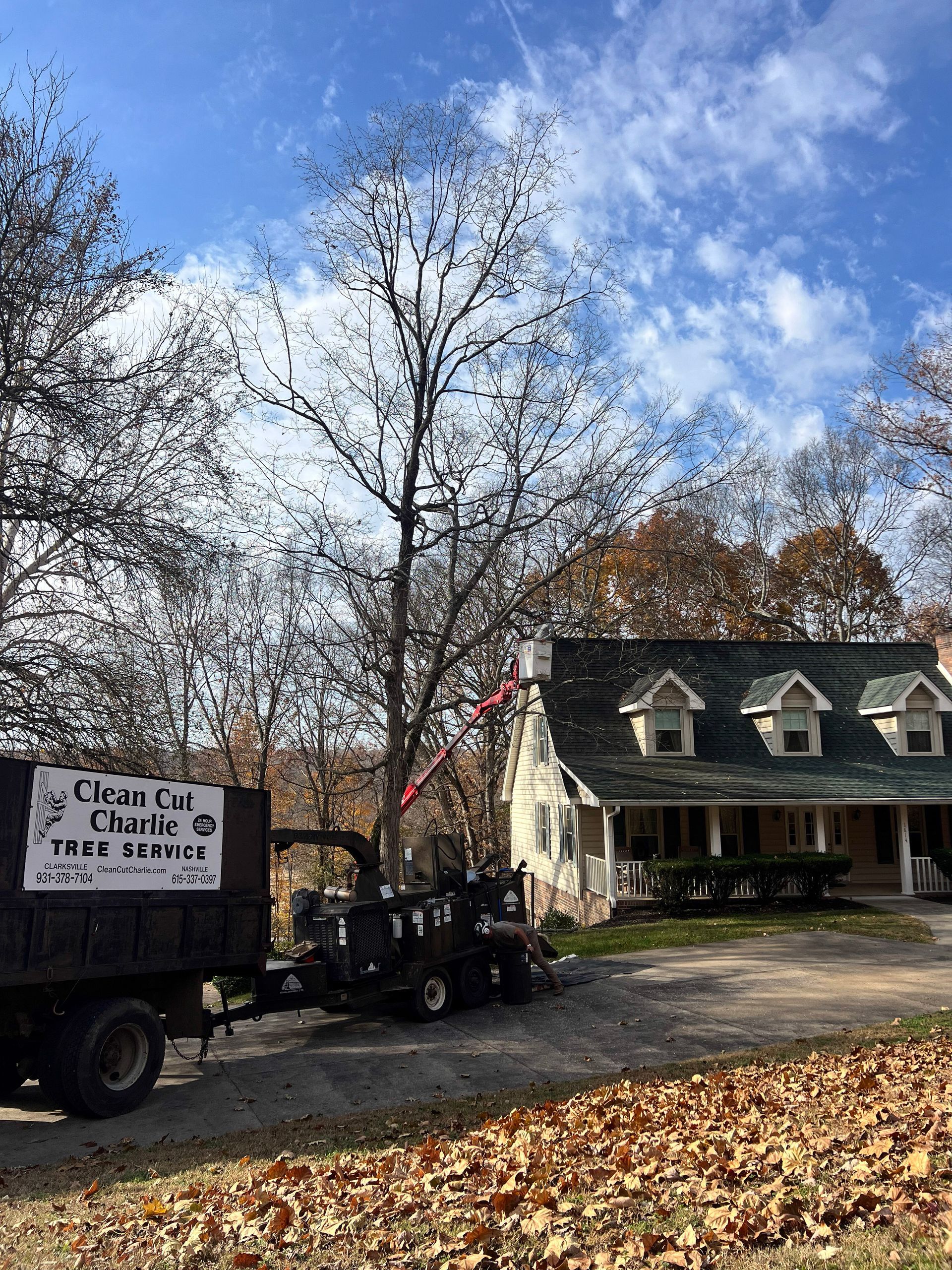 Tree removal service with truck and chipper in front of a house.