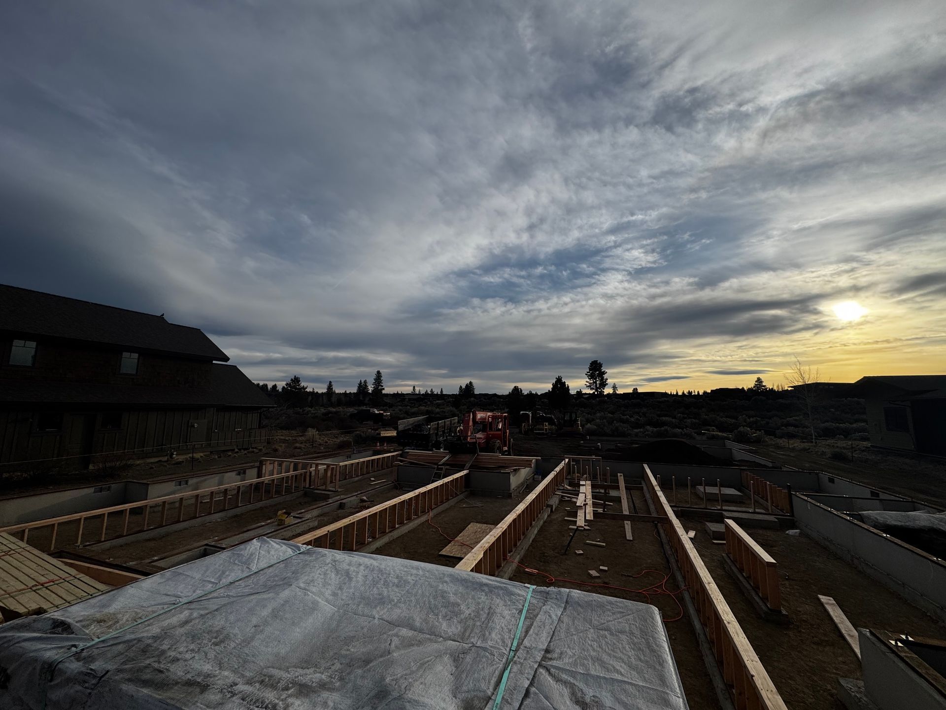 Construction site with foundation trenches at sunset under a cloudy sky