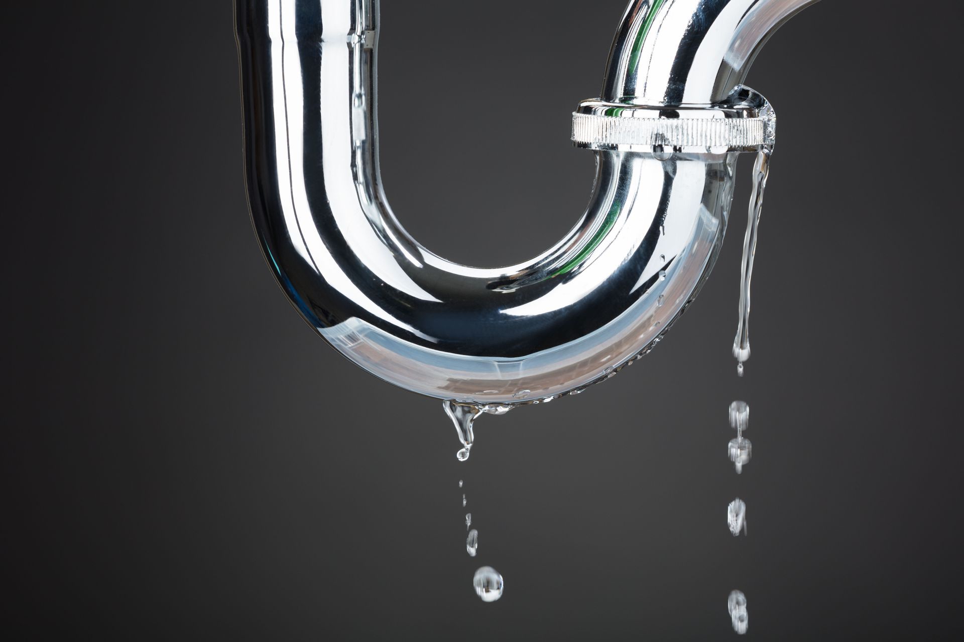 Chrome U-shaped pipe with dripping water against a dark background